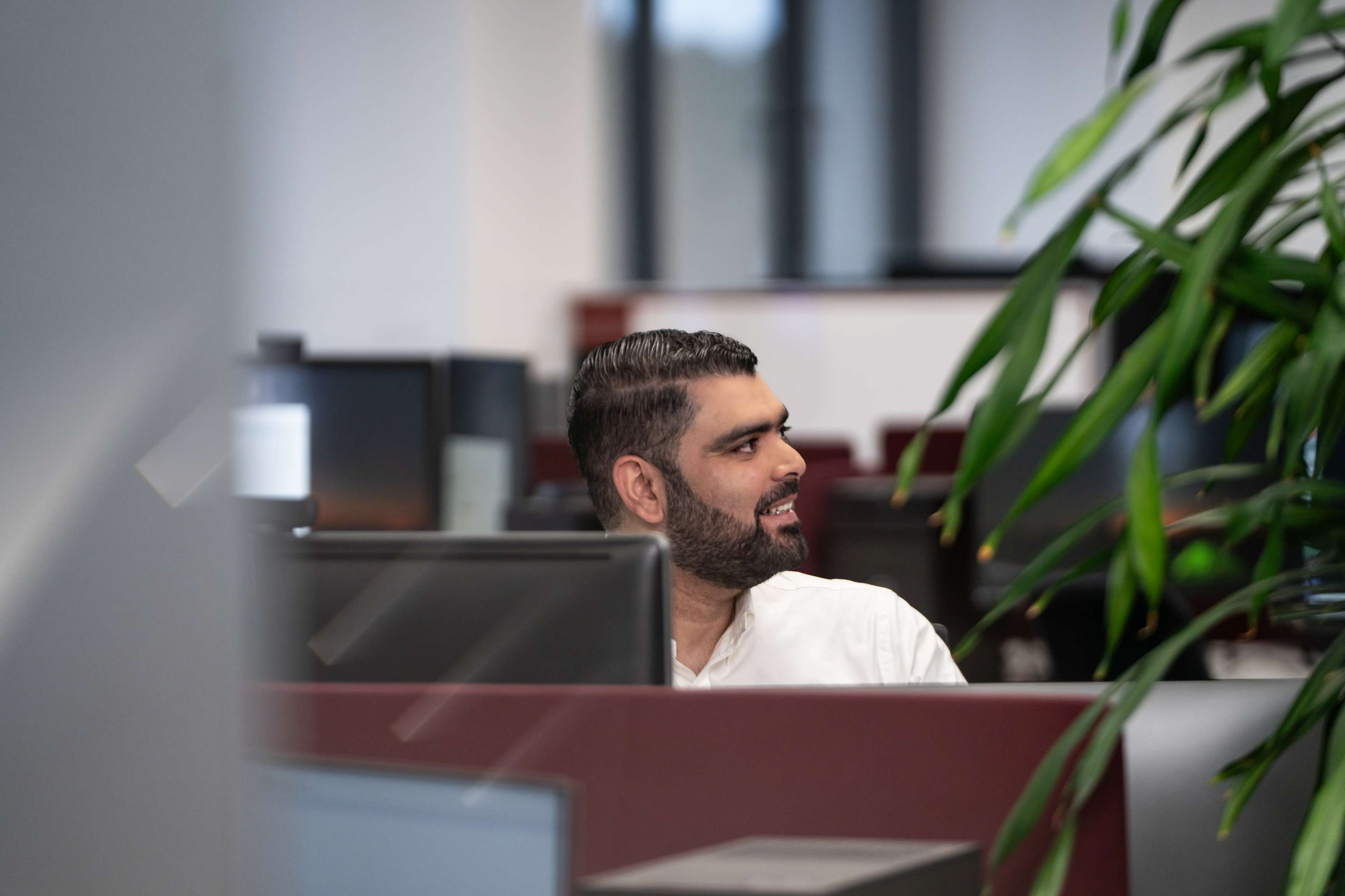 Ein Mann sitzt an einem Schreibtisch und schaut zur Seite.