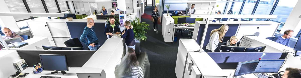 Ein Büroraum, fotografiert aus einem hohen Winkel mit verschiedenen Schreibtischen.