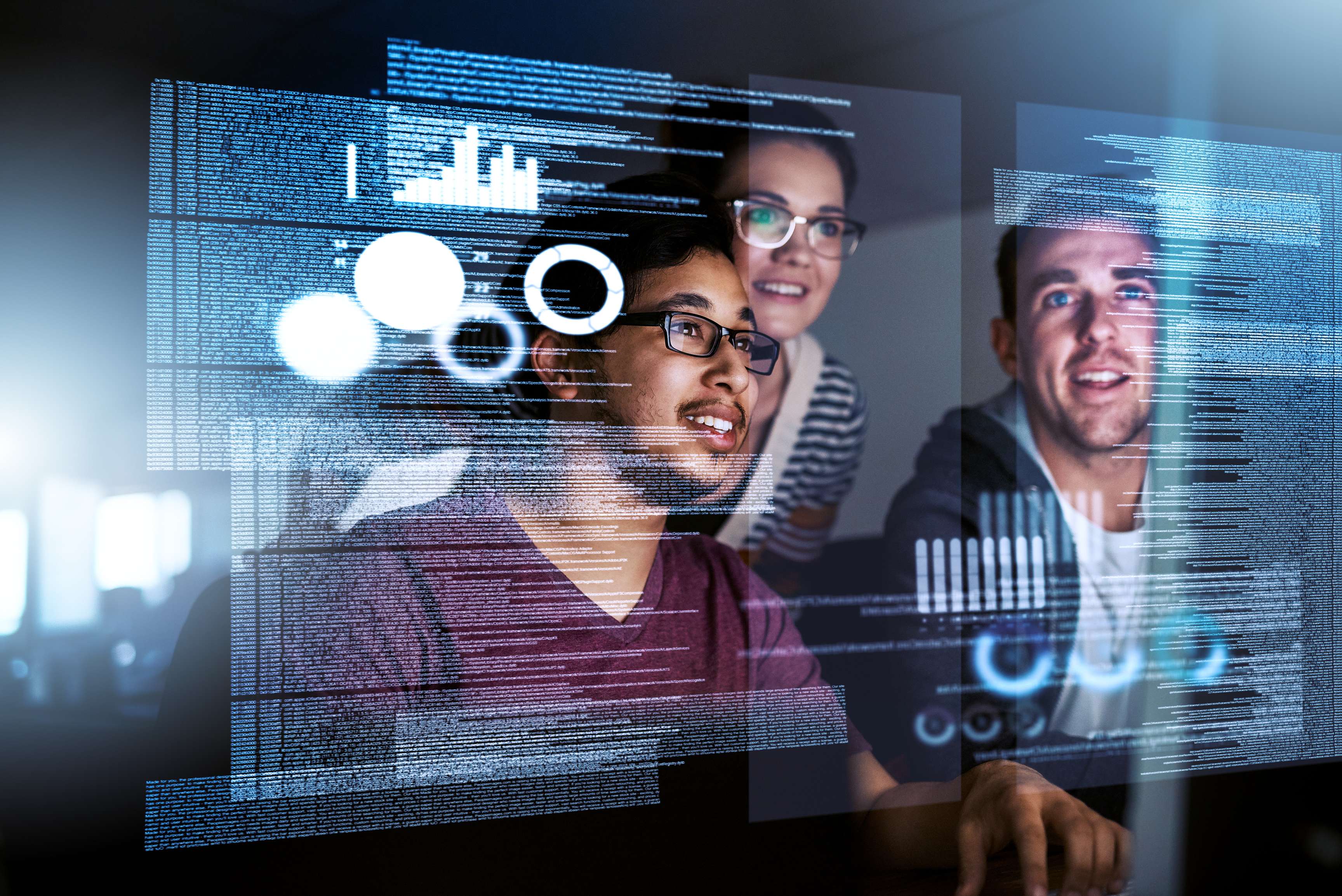 Three people look together at a screen that shows data sets and codes.