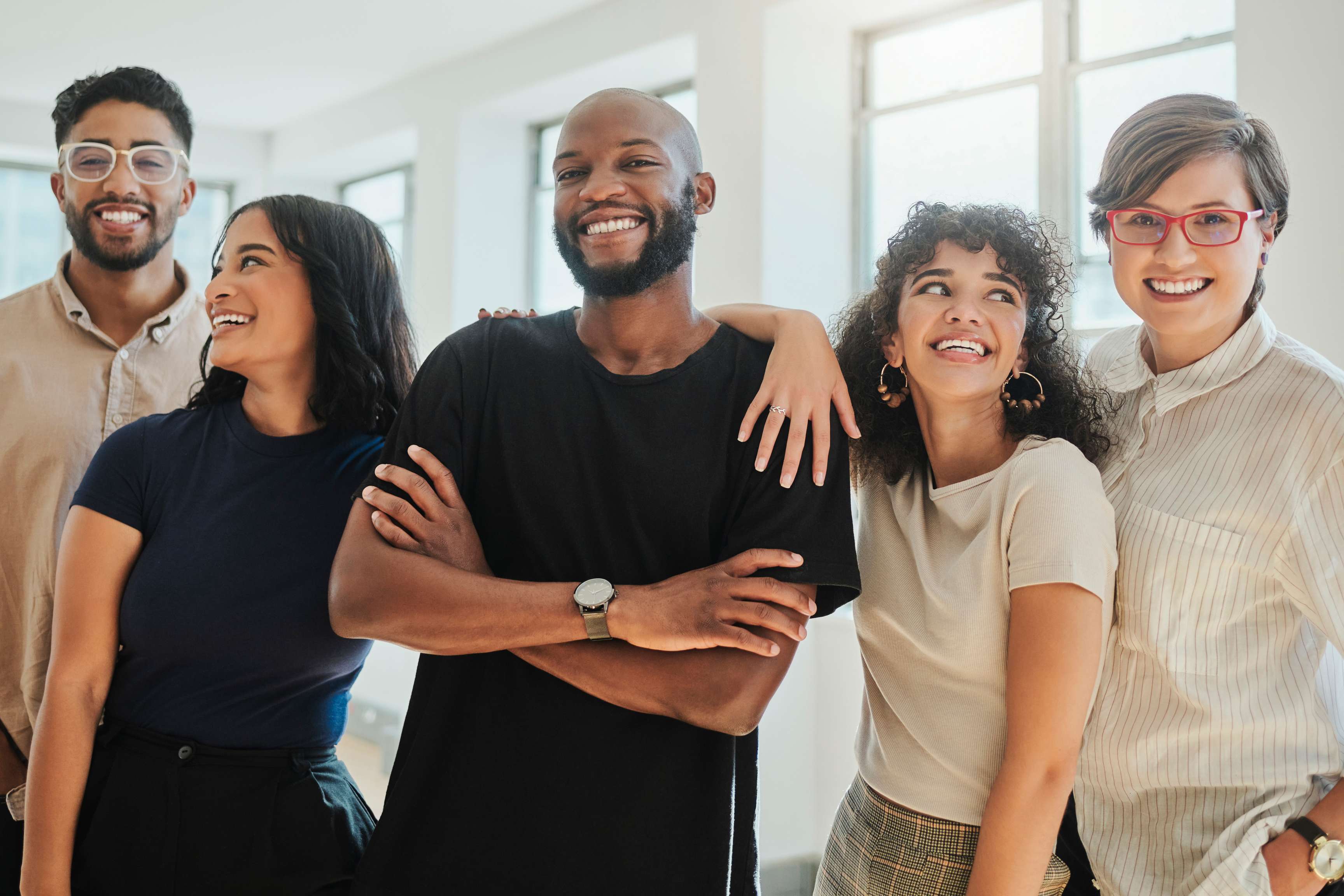 People standing together, arms around each other, smiling at the camera.