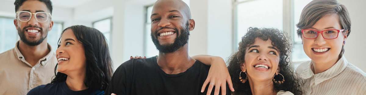 People standing together, arms around each other, smiling at the camera.