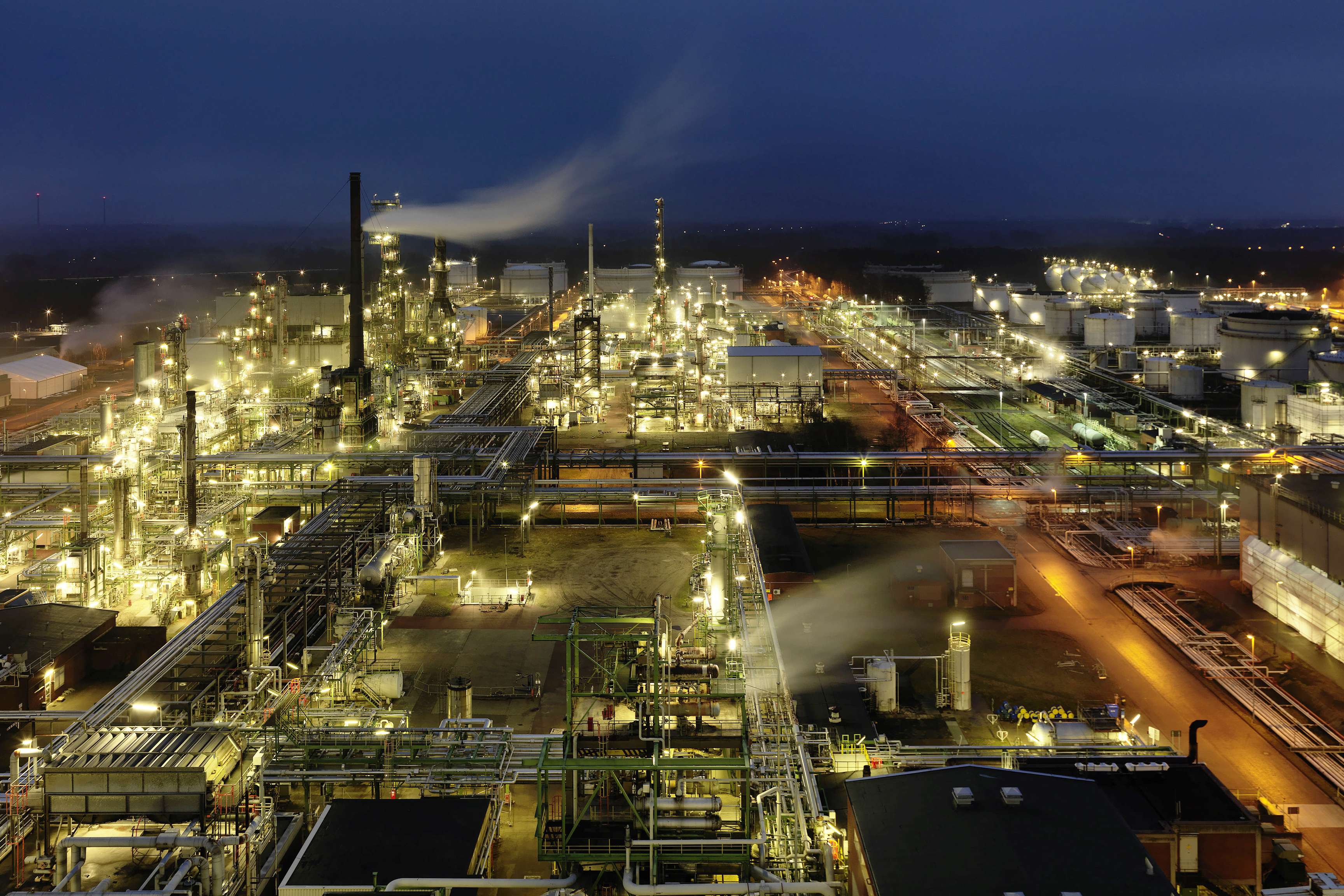 Picture of a refinery site in the dark on which numerous lights shine.