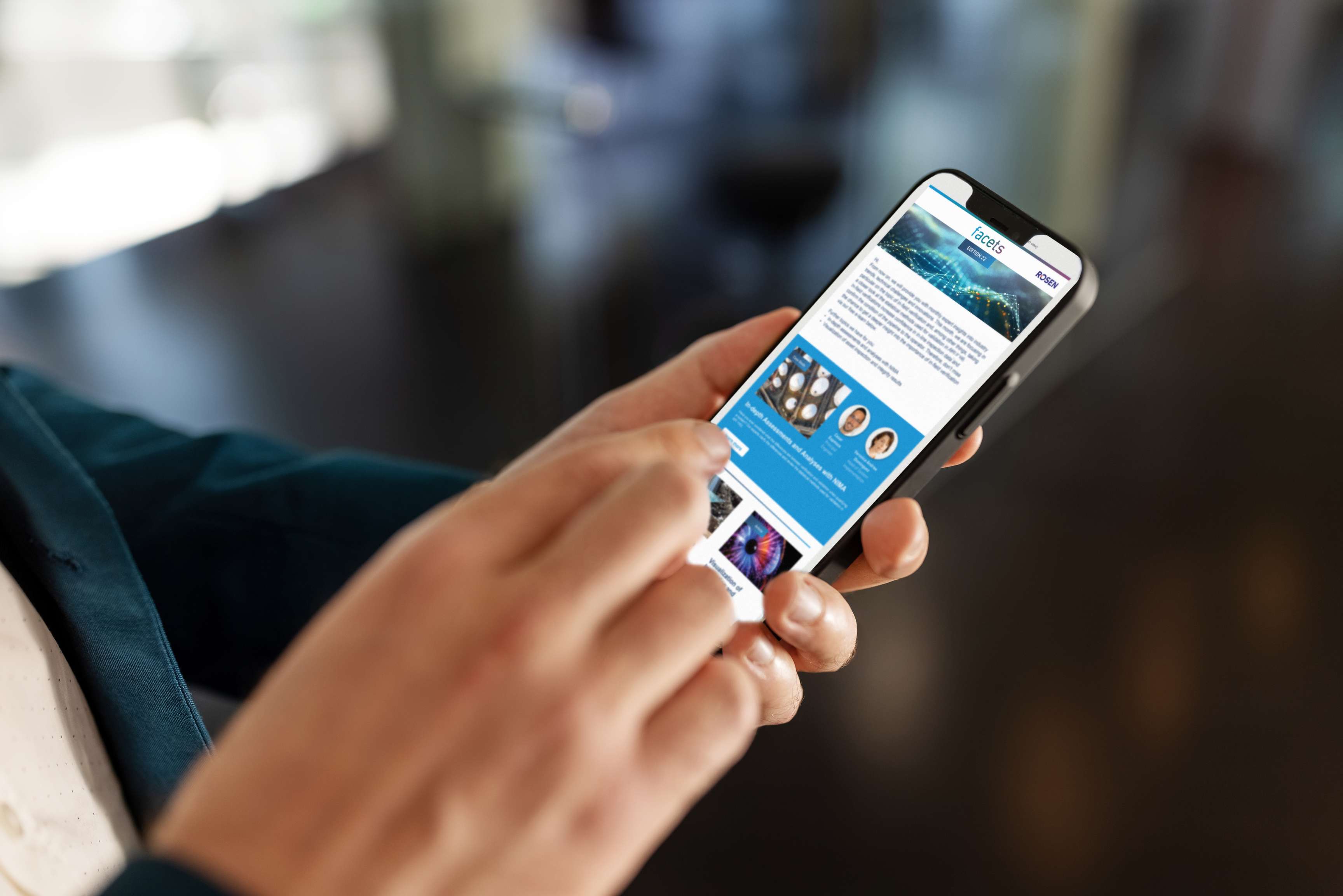 Close up of a hand holding a cell phone on which the facet newsletter can be seen.