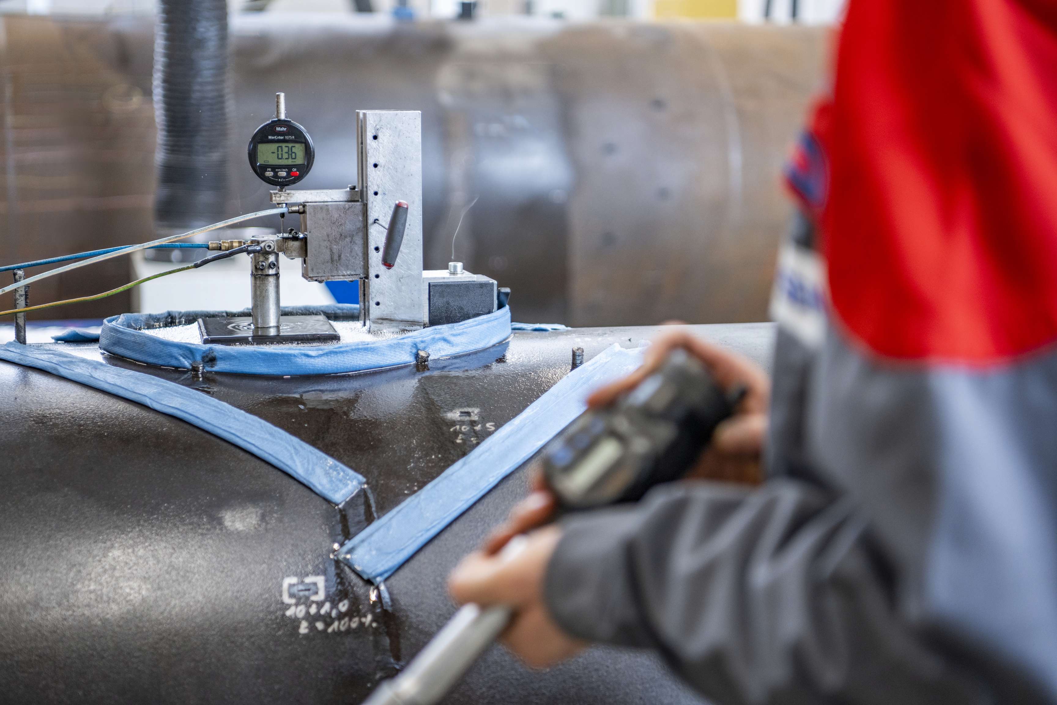 An employee stands in front of a measuring device resting on a pipeline.