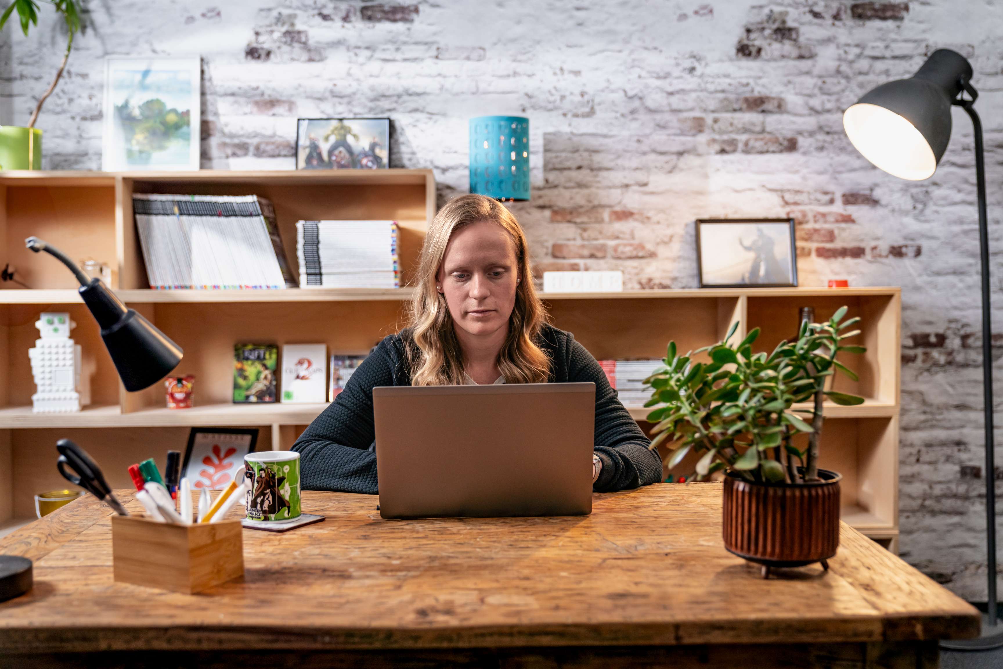 Eine Frau sitzt an einem Schreibtisch und schaut in ihr Notebook.