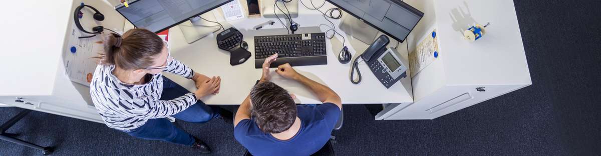 Ein Schreibtisch in einem Büroraum, fotografiert aus der Vogelperspektive.