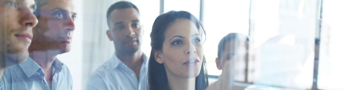 View through a glass pane on several people looking at something that is written on the glass pane.