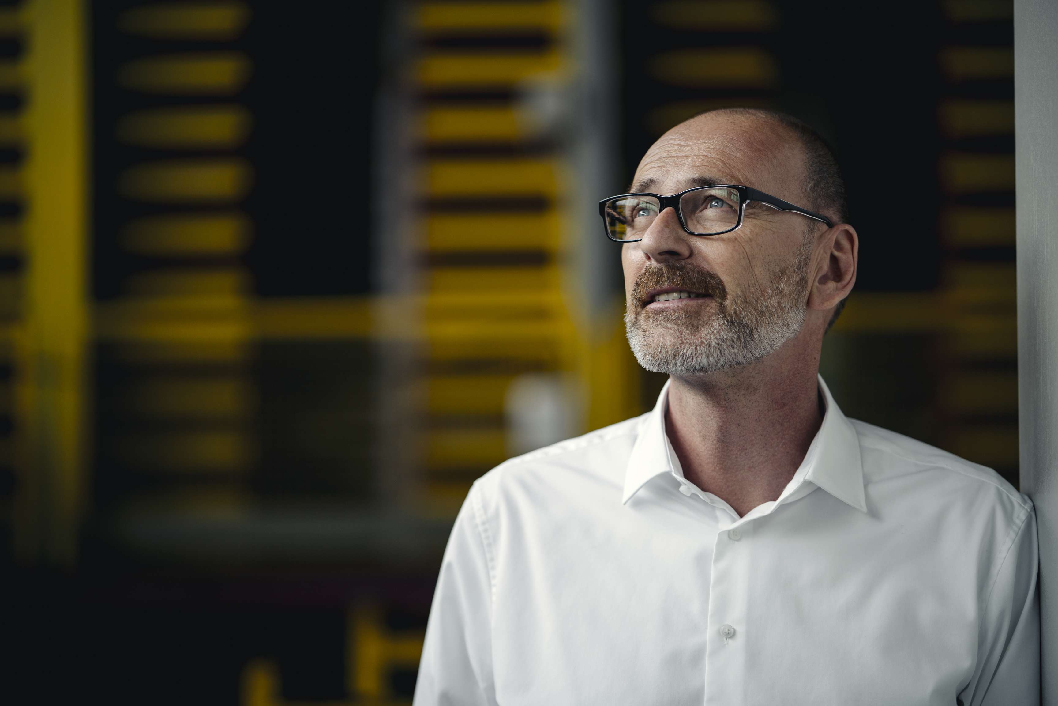 Man with glasses looks sideways into distance.