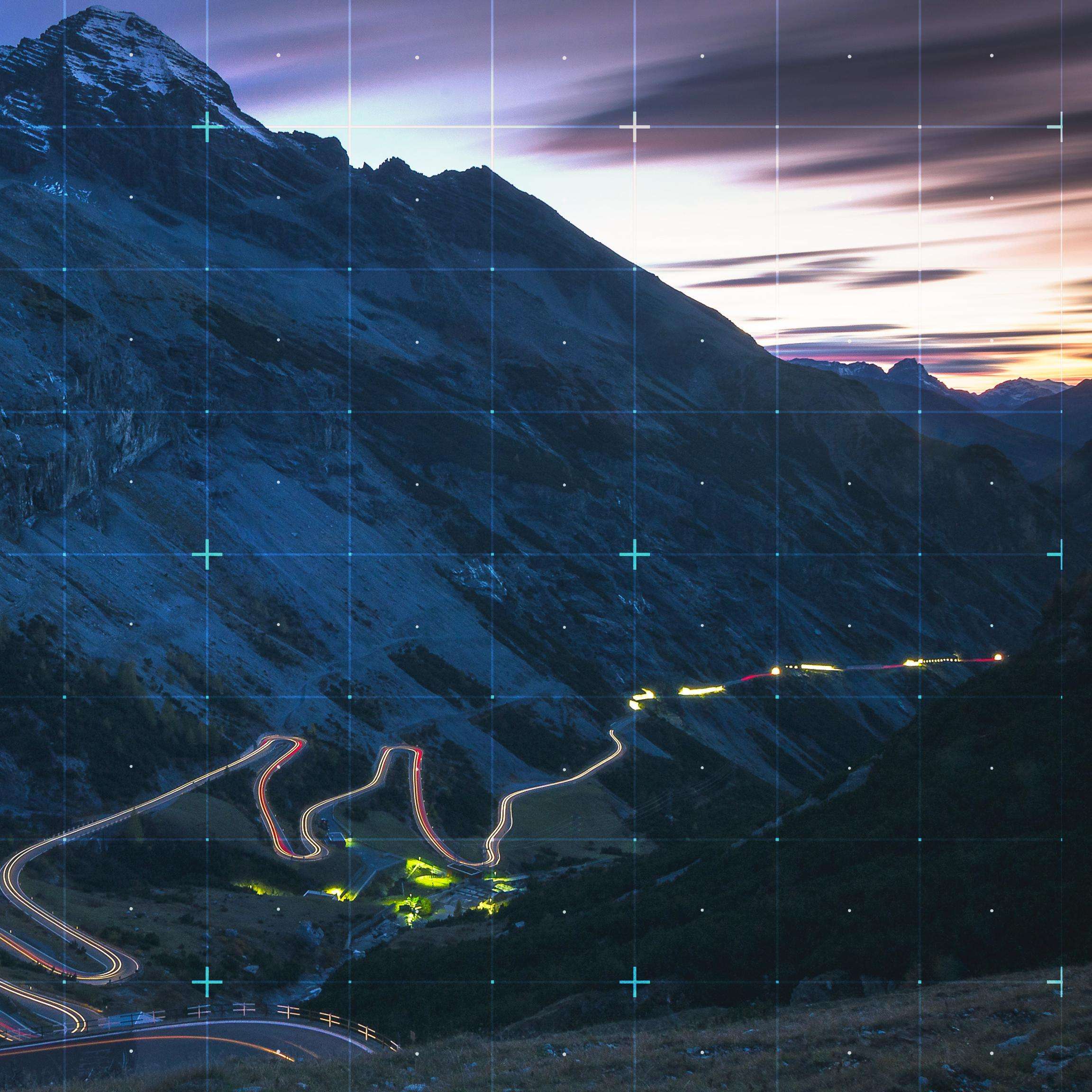 Rasterized view of dark mountain landscape with lighted road passing through it.