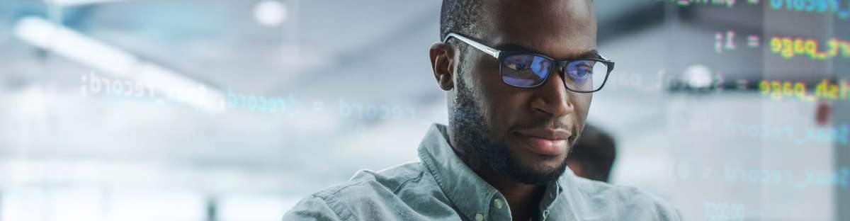 Portrait of man with glasses sitting in front of laptop and programming.