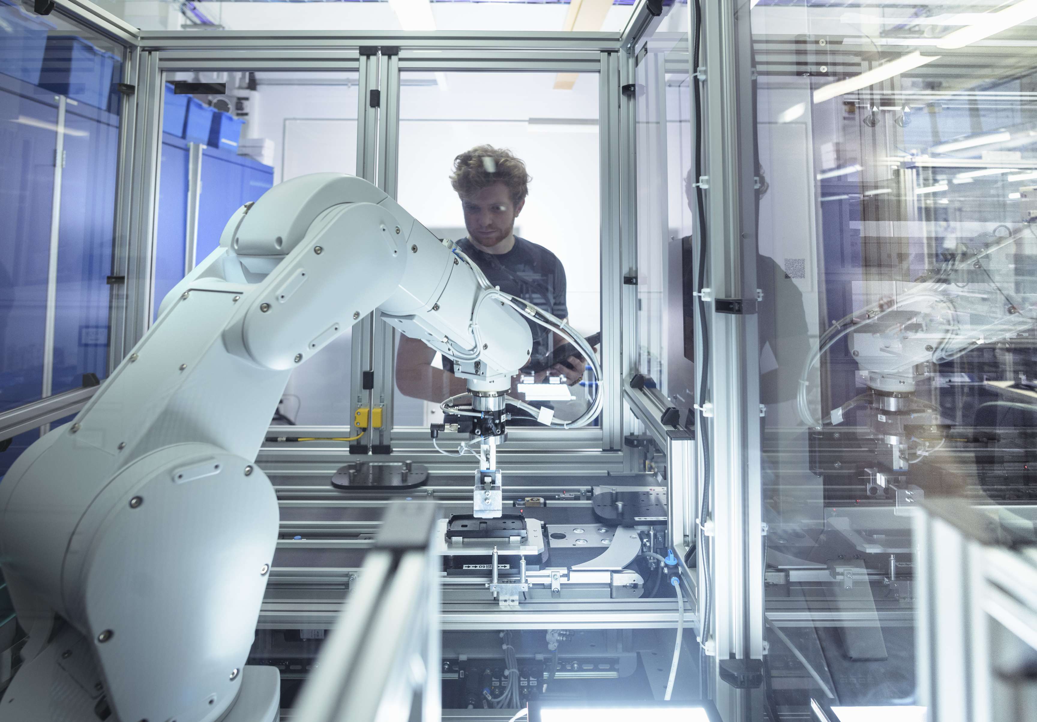 Employee looking at gripper arm from a machine.