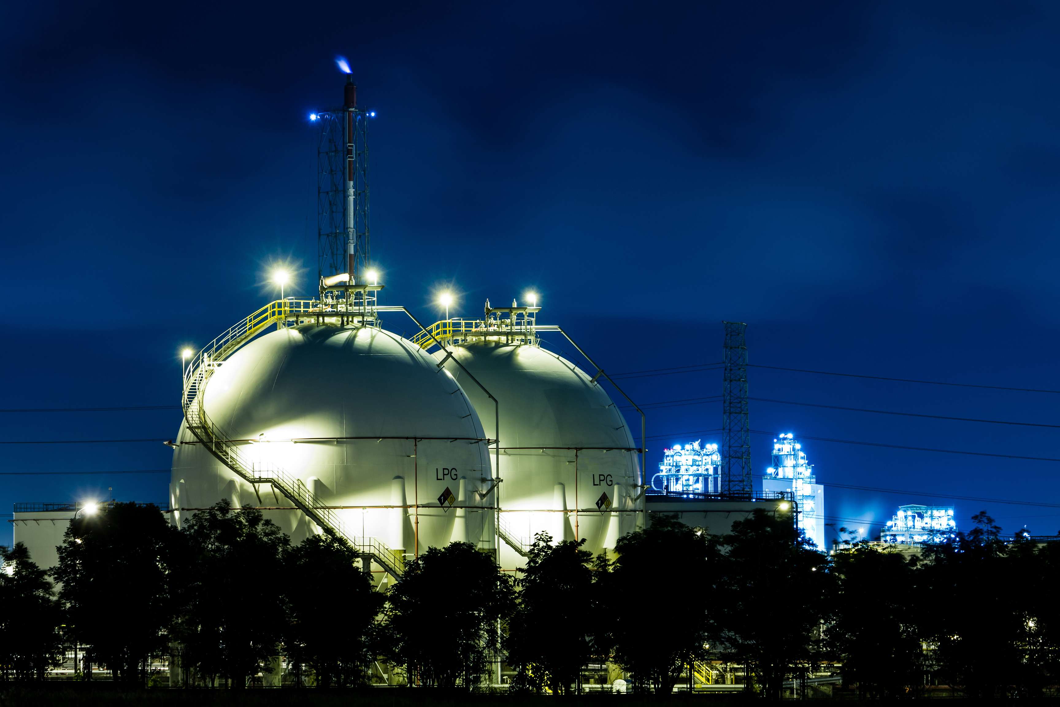 Two illuminated pressure vessels in front of a night sky.