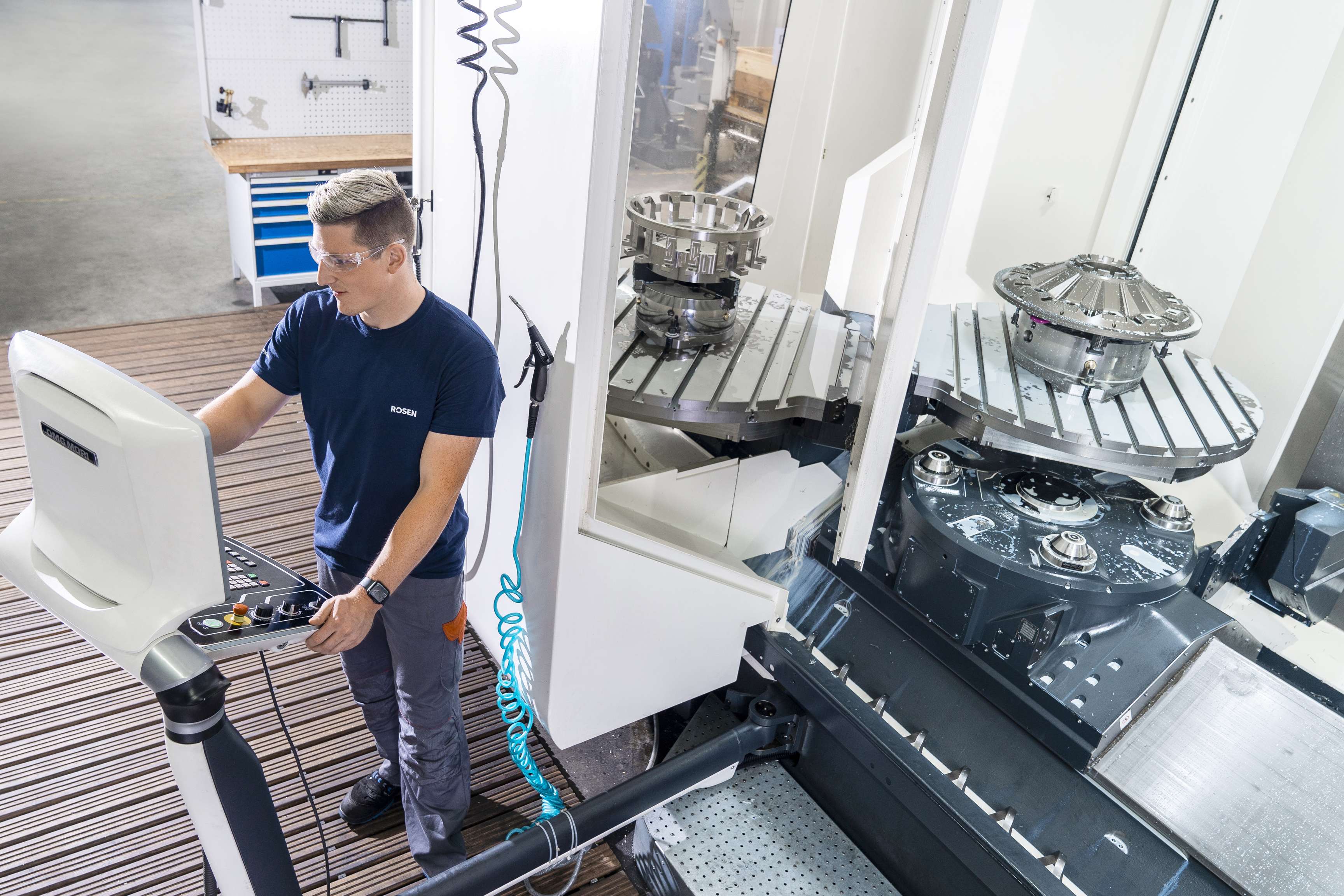 Factory employee with safety glasses operates a machine.