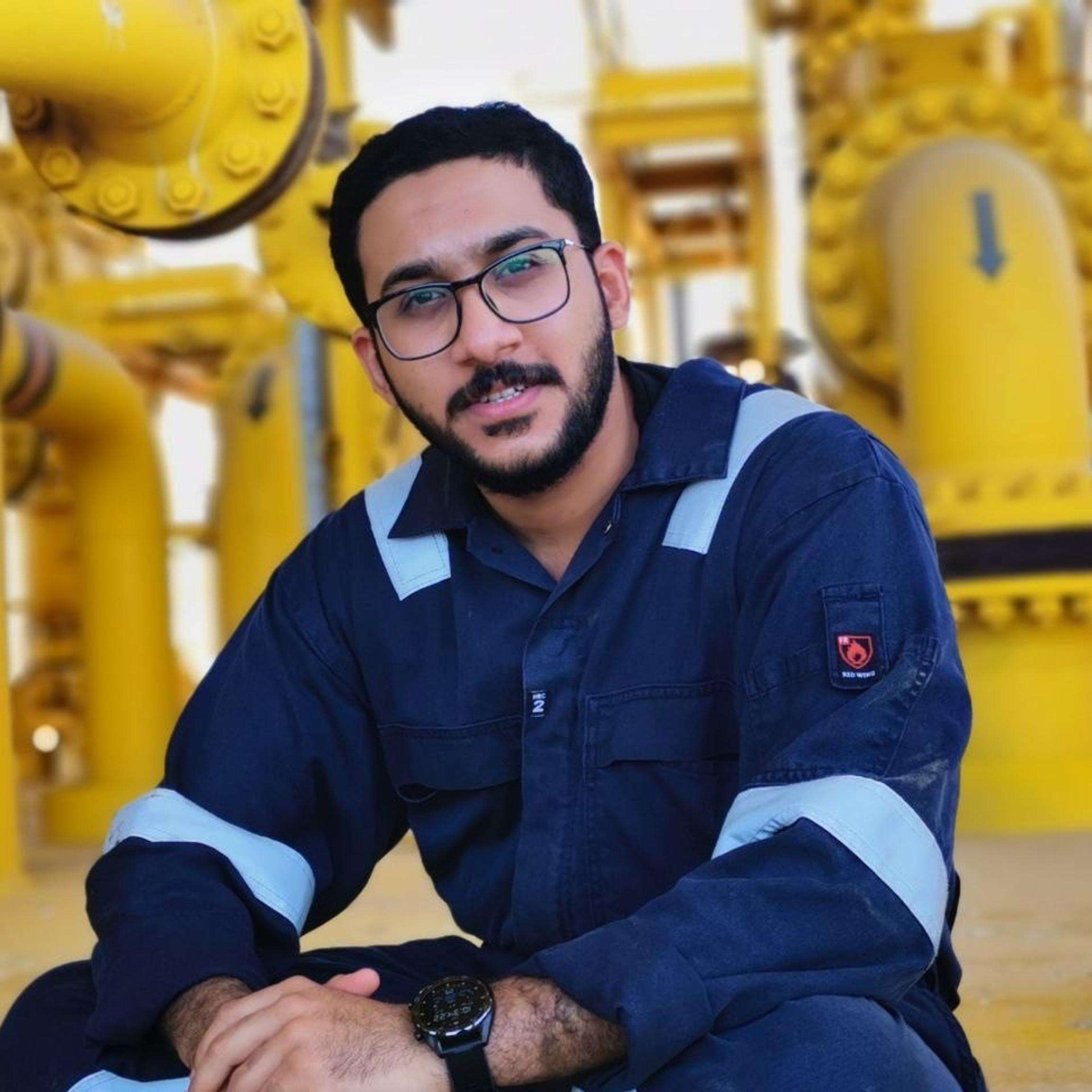 A man looking into the camera while sitting in front of an industrial asset.