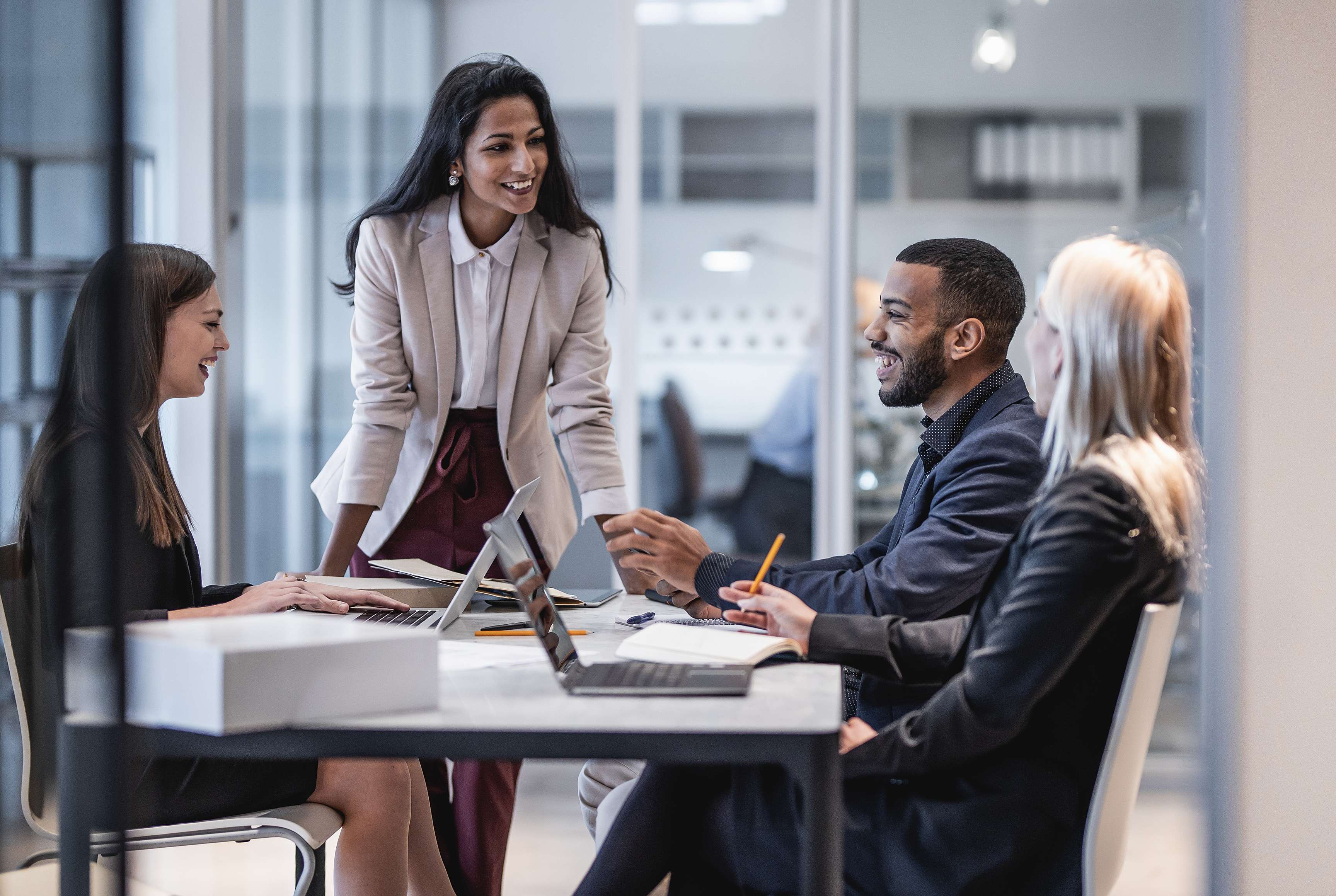 Four people laughing at a meeting table.