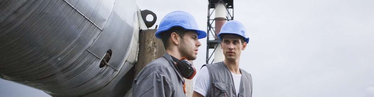 Two employees are walking, behind them is a pipeline.