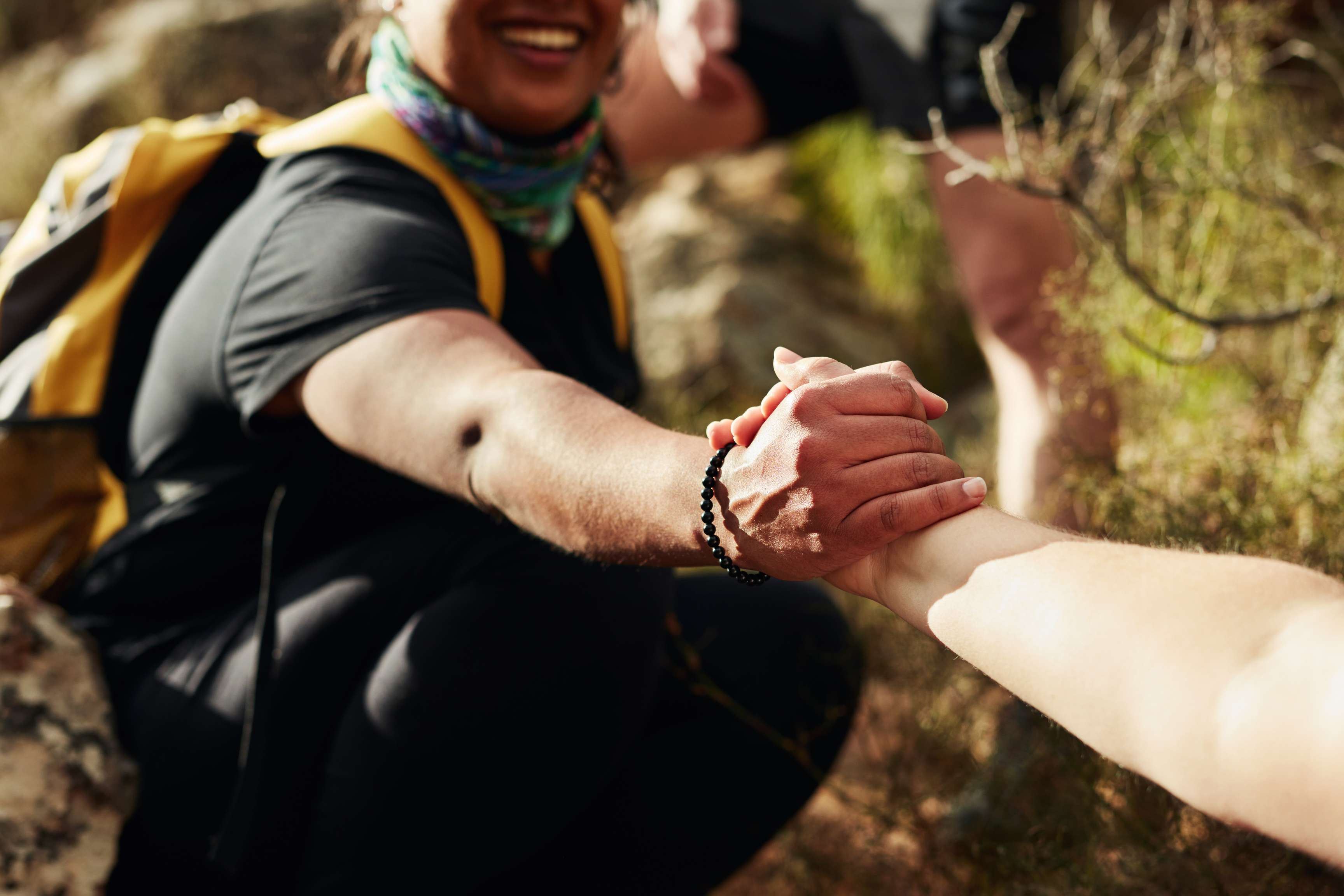 One person grabs a woman by the hand to support her on a walk, the hands are in the foreground.