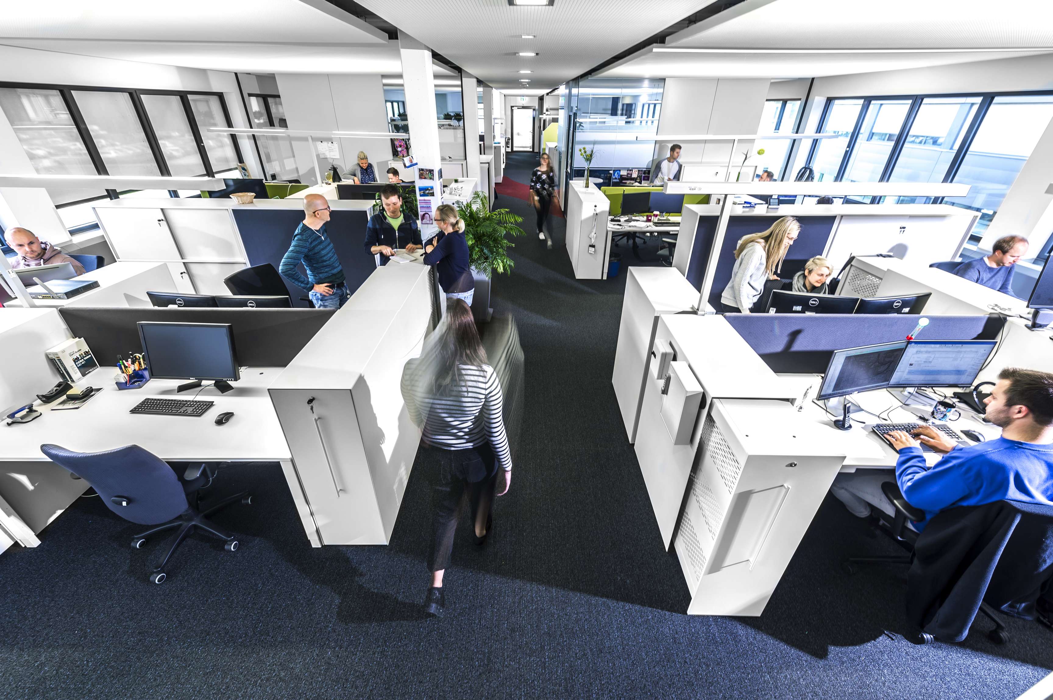 Ein Büroraum, fotografiert aus einem hohen Winkel mit verschiedenen Schreibtischen.