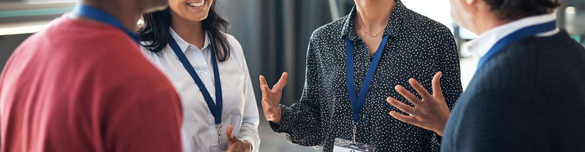 Photo of a group of business people standing in a circle at a conference, talking and networking.