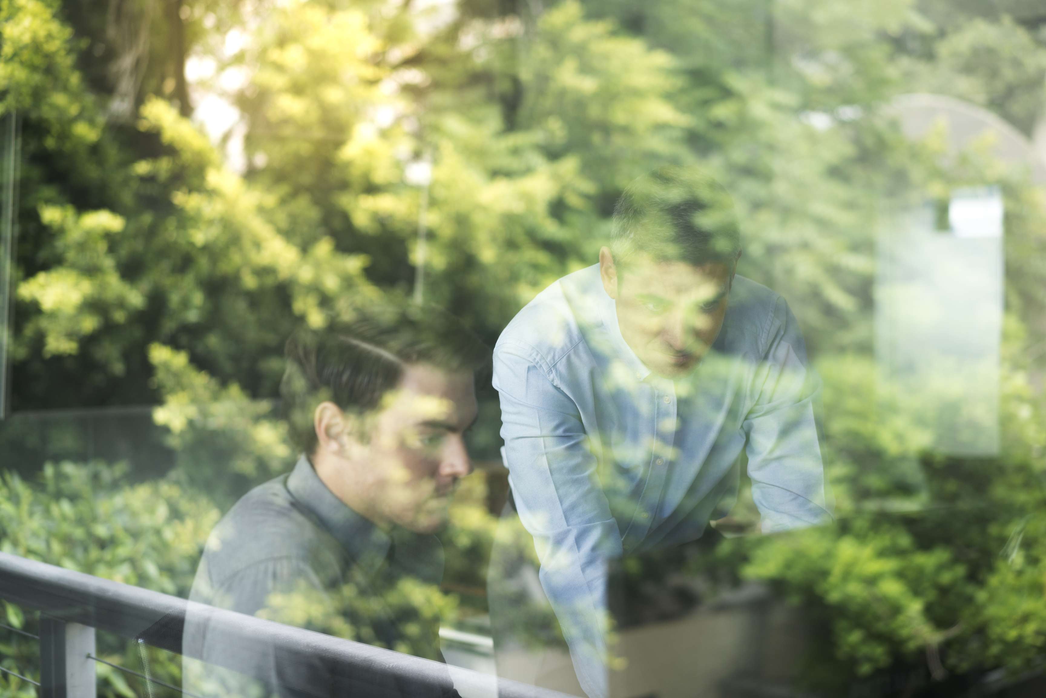 Business people looking at computer through the window.