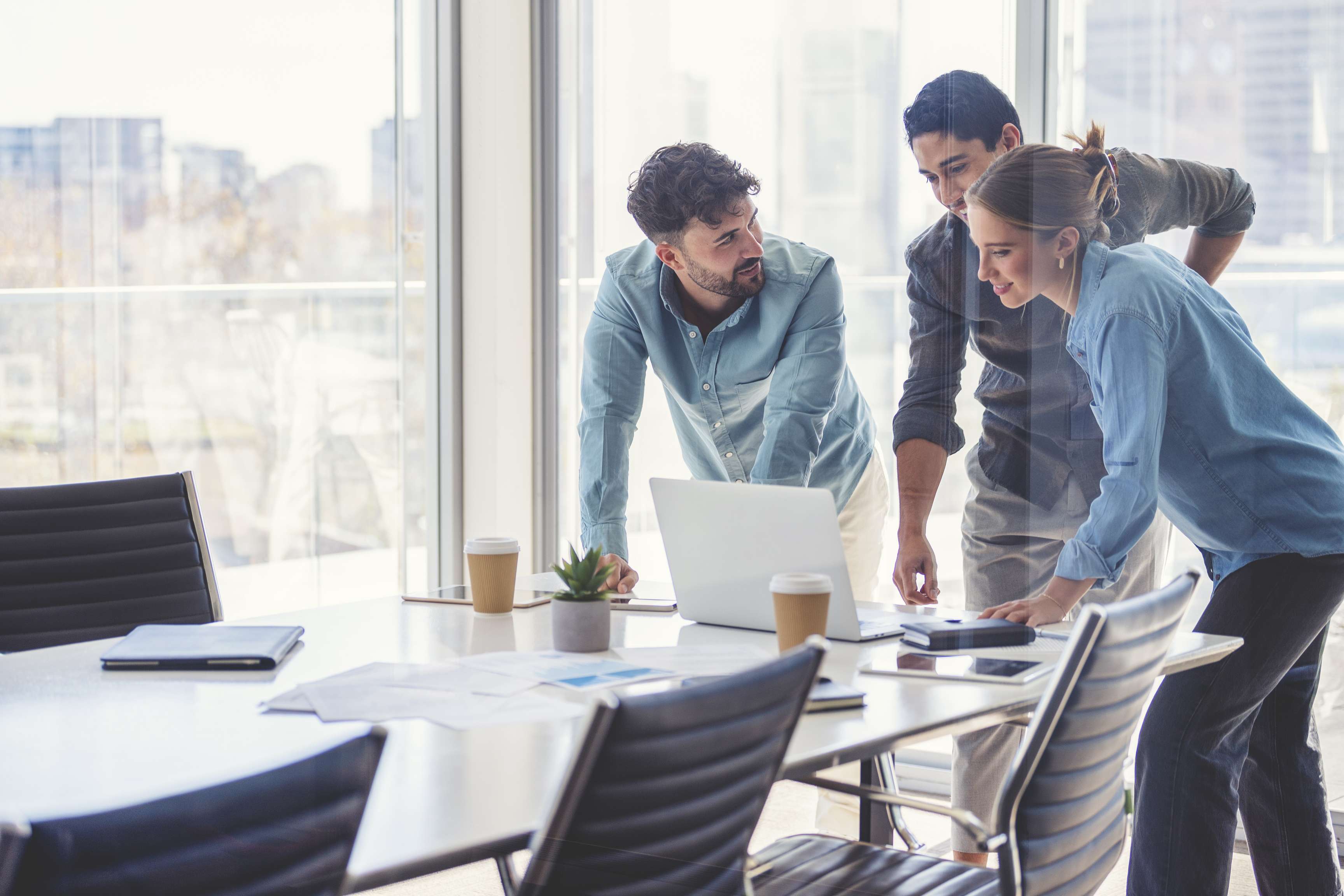 Three people standing at a desk in a business meeting