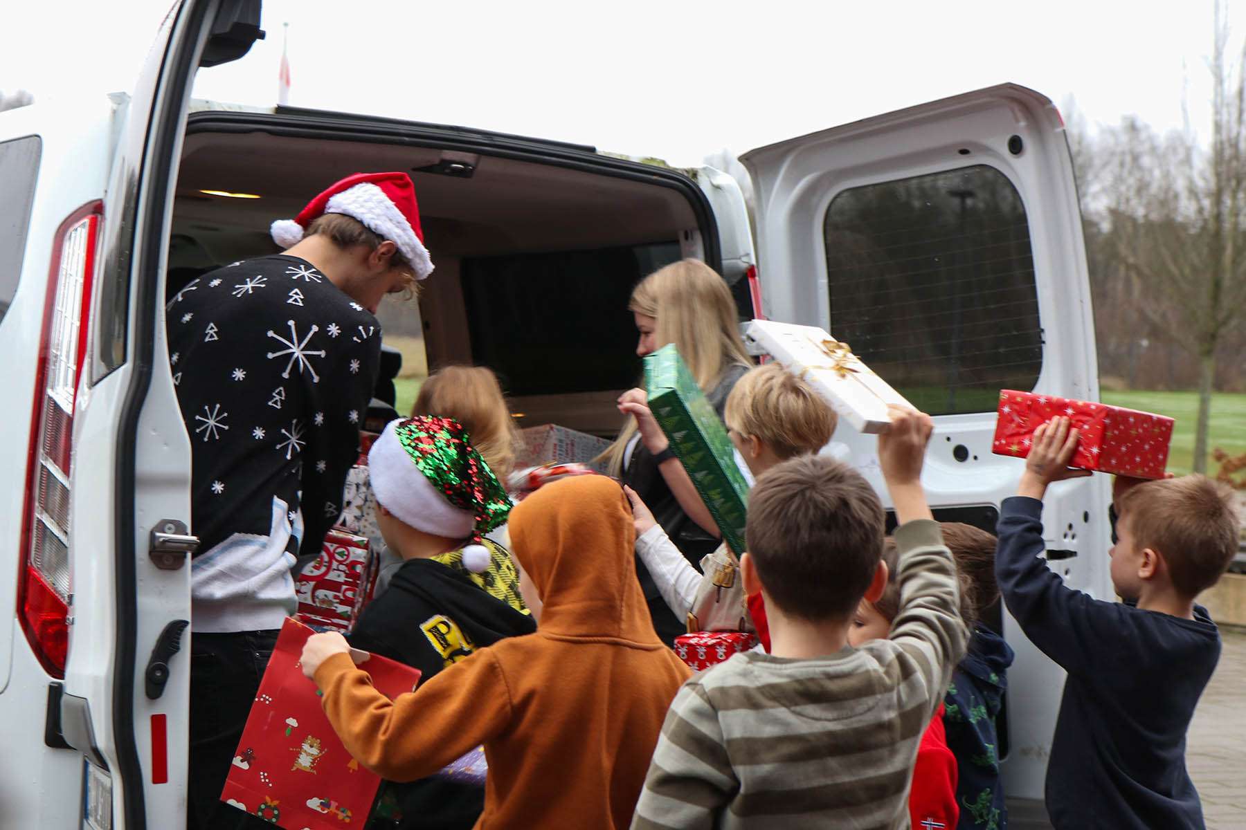 Children and adults fill a car with Christmas presents.