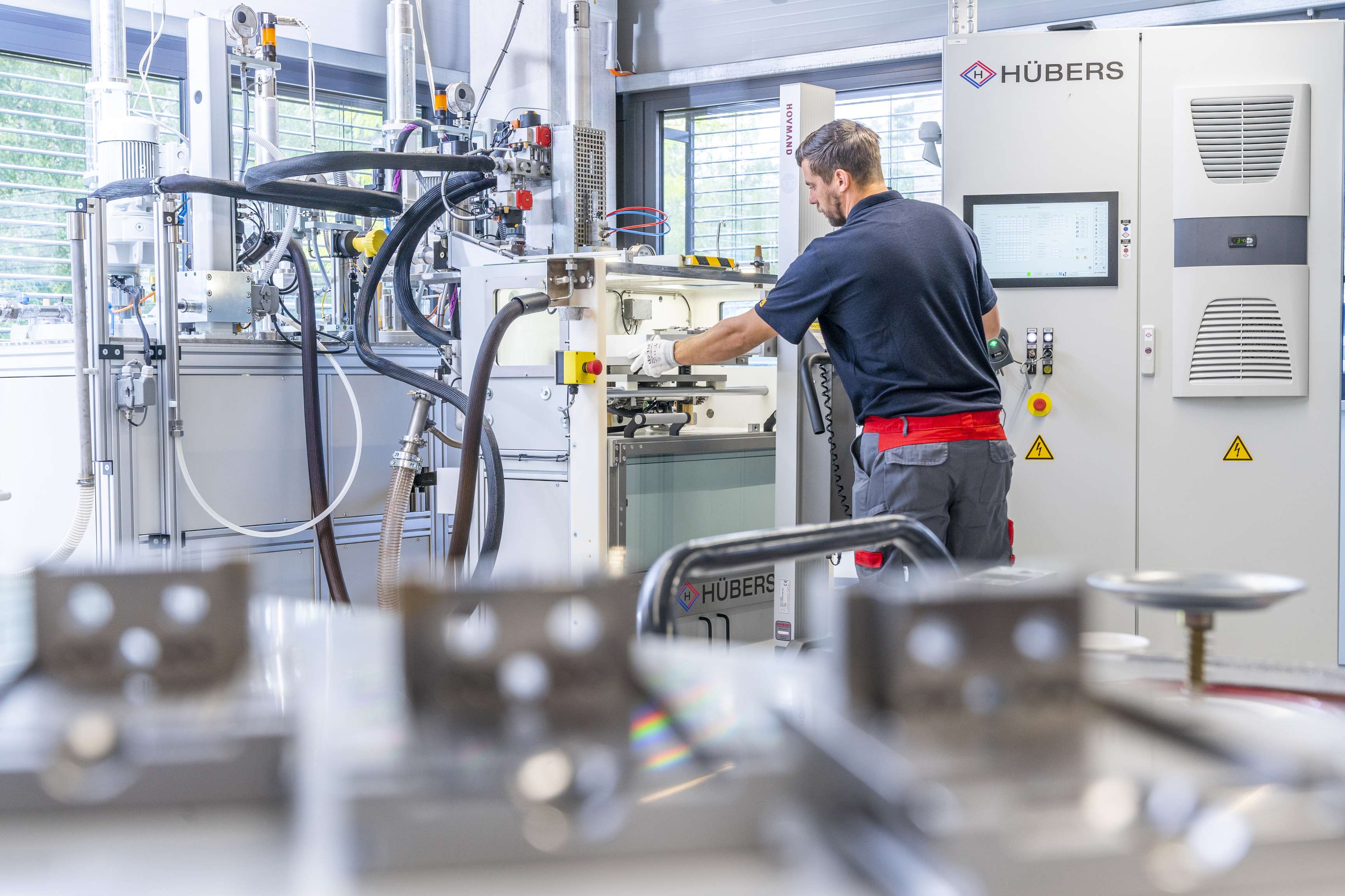 Ein ROSEN Mitarbeiter in der Sensorfertigung steht an einer Maschine an der viele Schläuche angeschlossen sind und bedient diese.