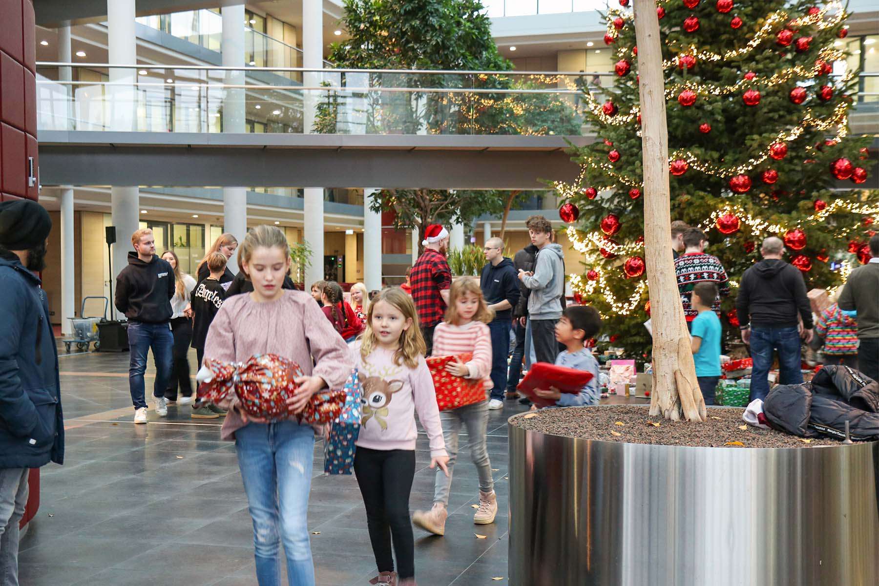 Children carrying Christmas presents for donation.