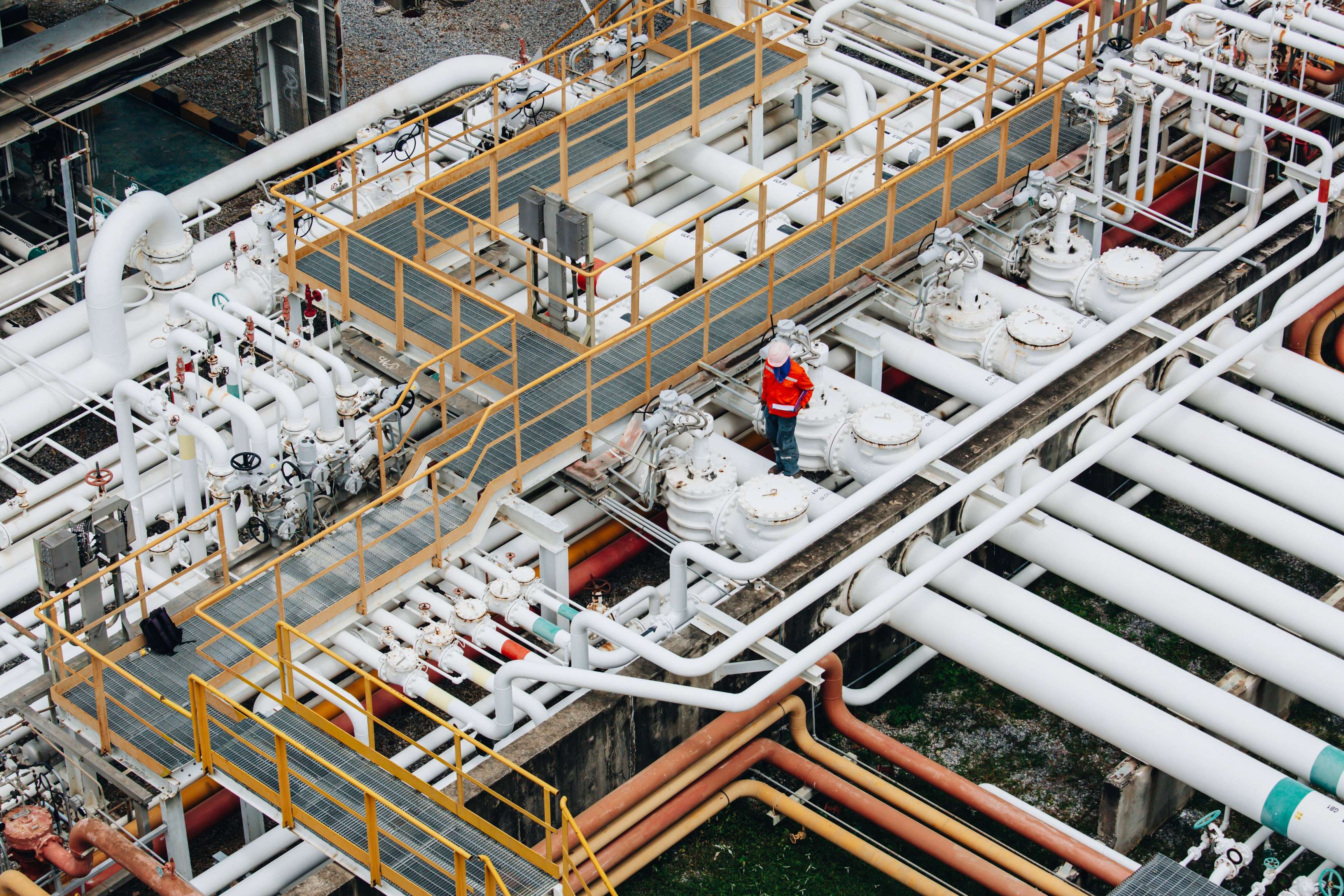 Bird's eye view of pipe system with an expert in orange overalls on the right.