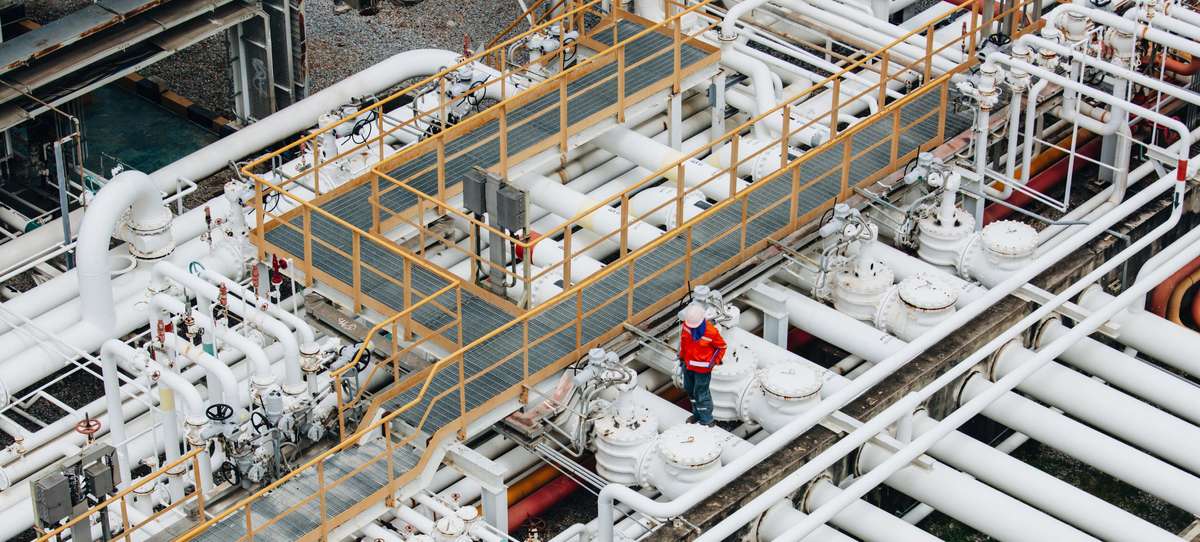 Bird's eye view of pipe system with an expert in orange overalls on the right.