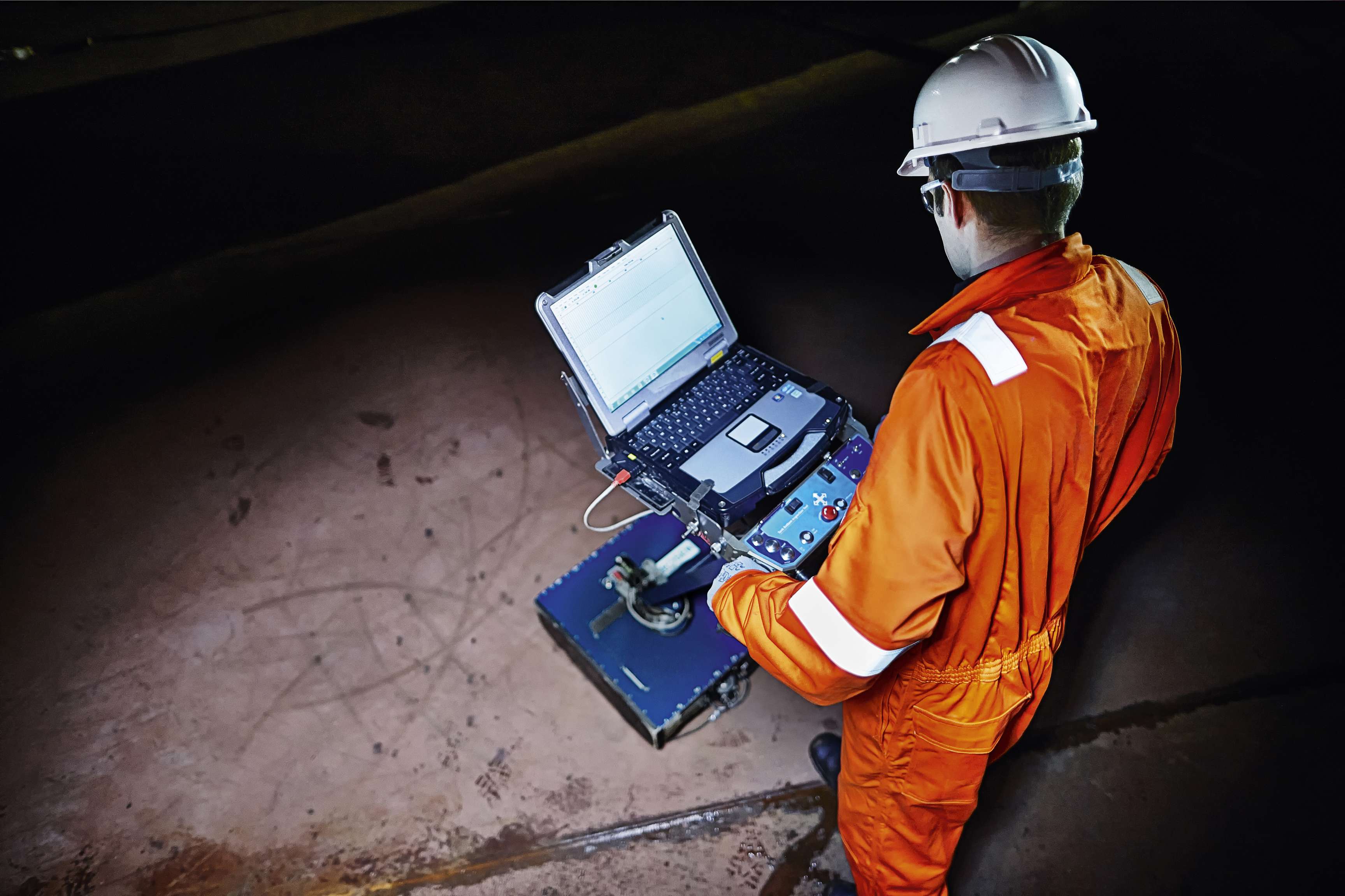 ROSEN expert in orange jumpsuit in a dark tank inspecting the tank bottom with the TBIT Ultra.