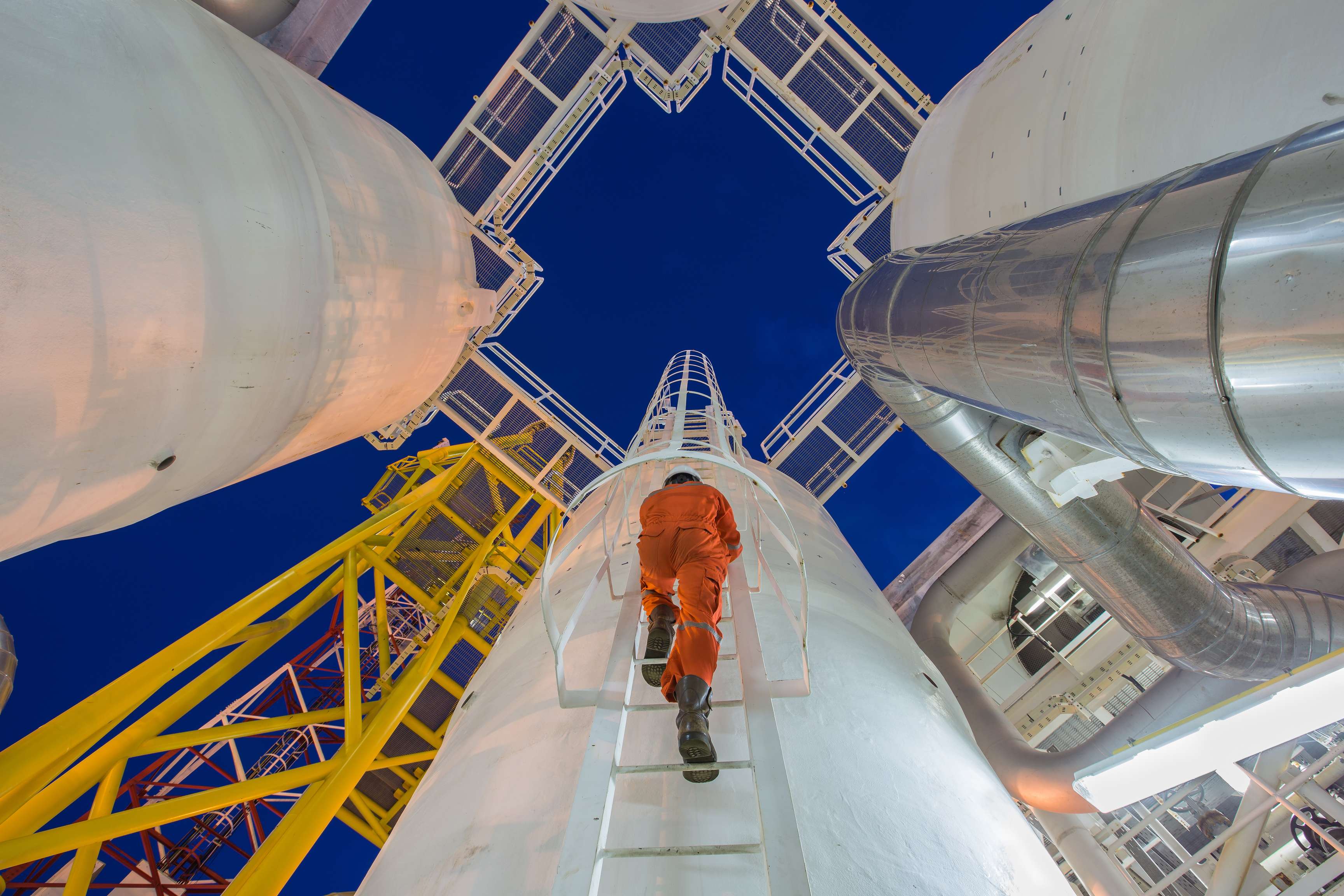 Expert climbing on a cylindrical pressure vessel at night.