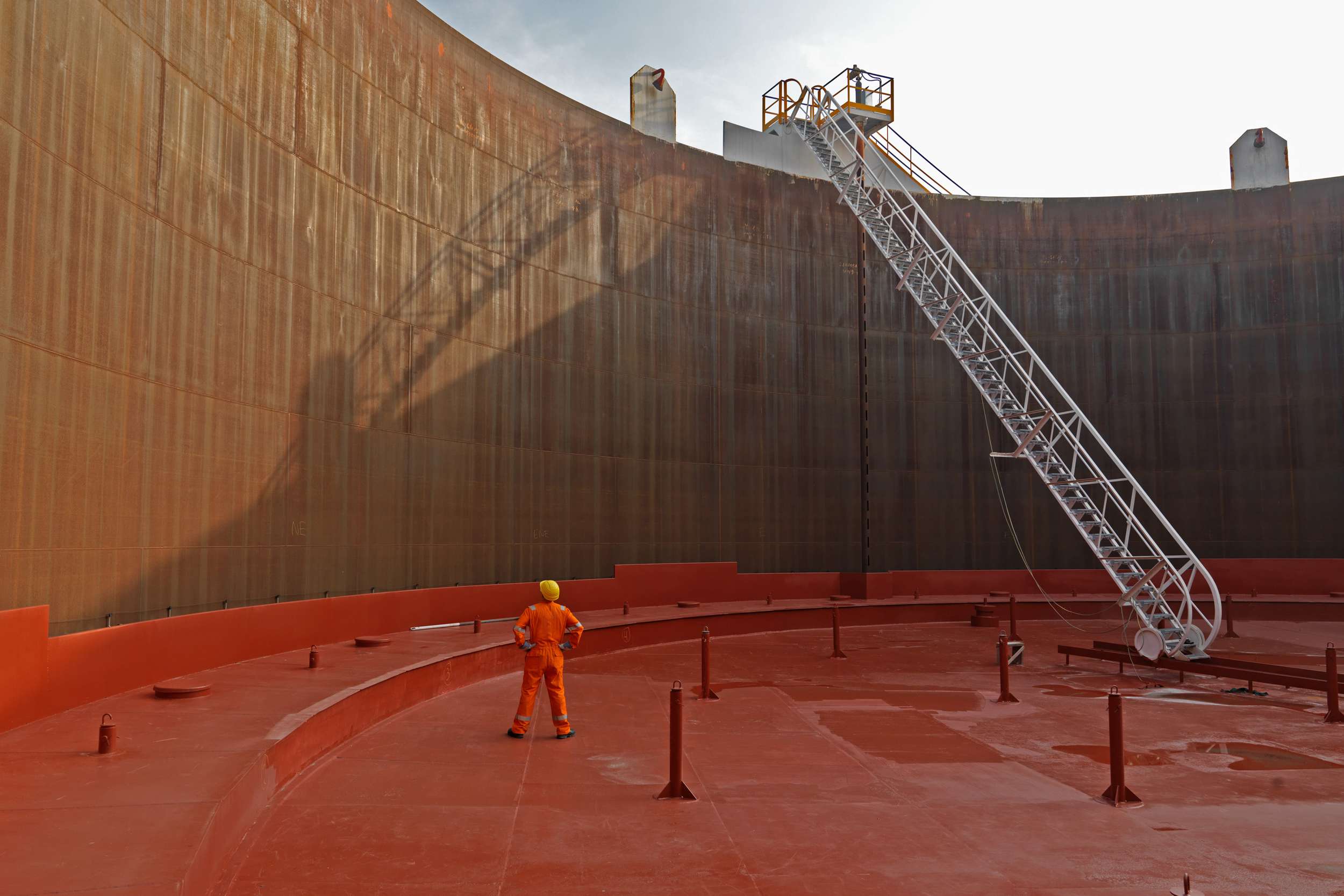 ROSEN expert in orange overall in the middle of a large tank without a roof on an orange ground.