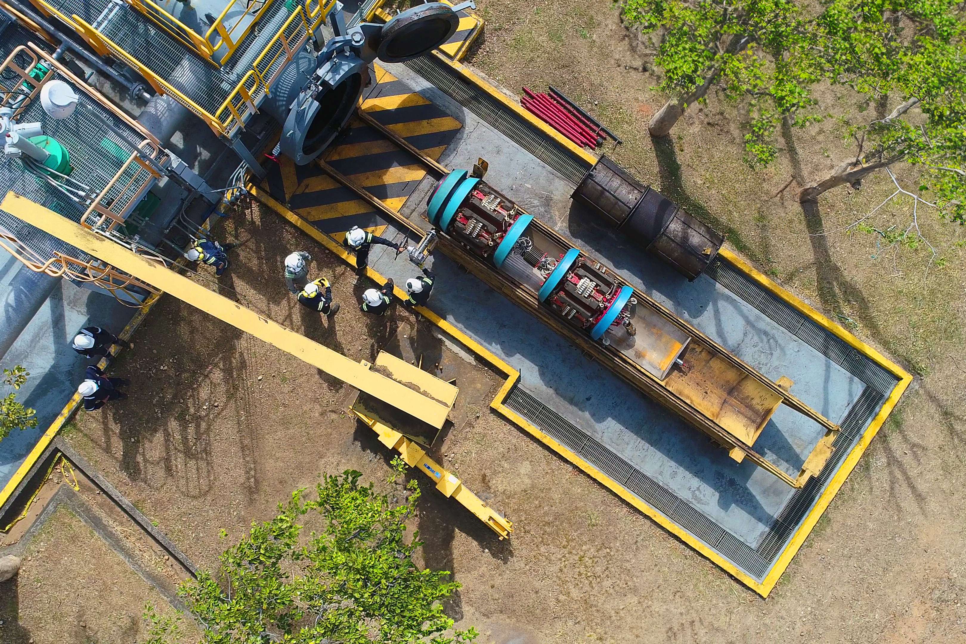 Aerial view of five engineers next to an open pipeline in front of which an in-line inspection tool is standing on a carrier and is to be launched into the pipeline. 