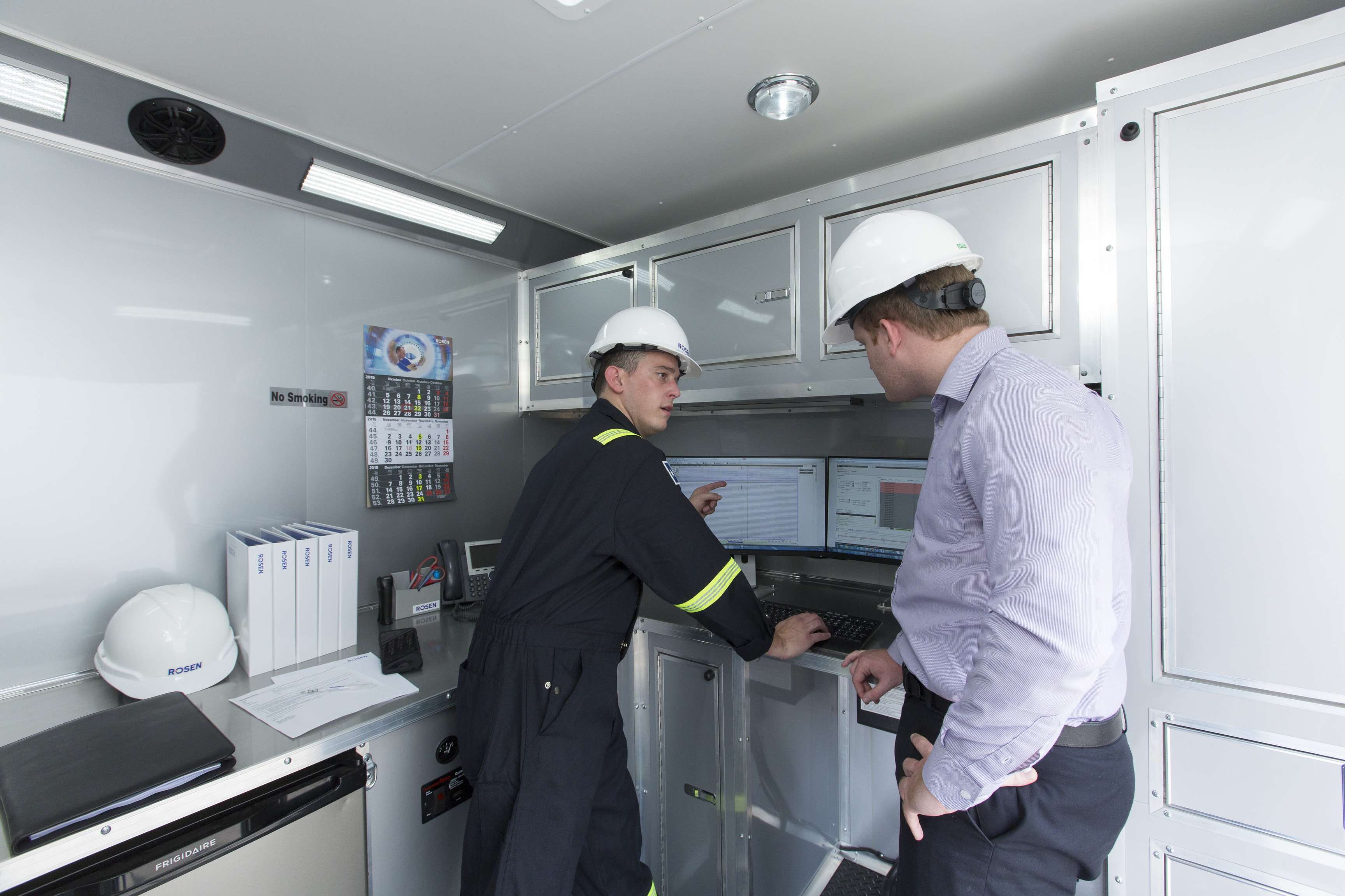 Onsite field technician reviewing data on a computer with a on looker.