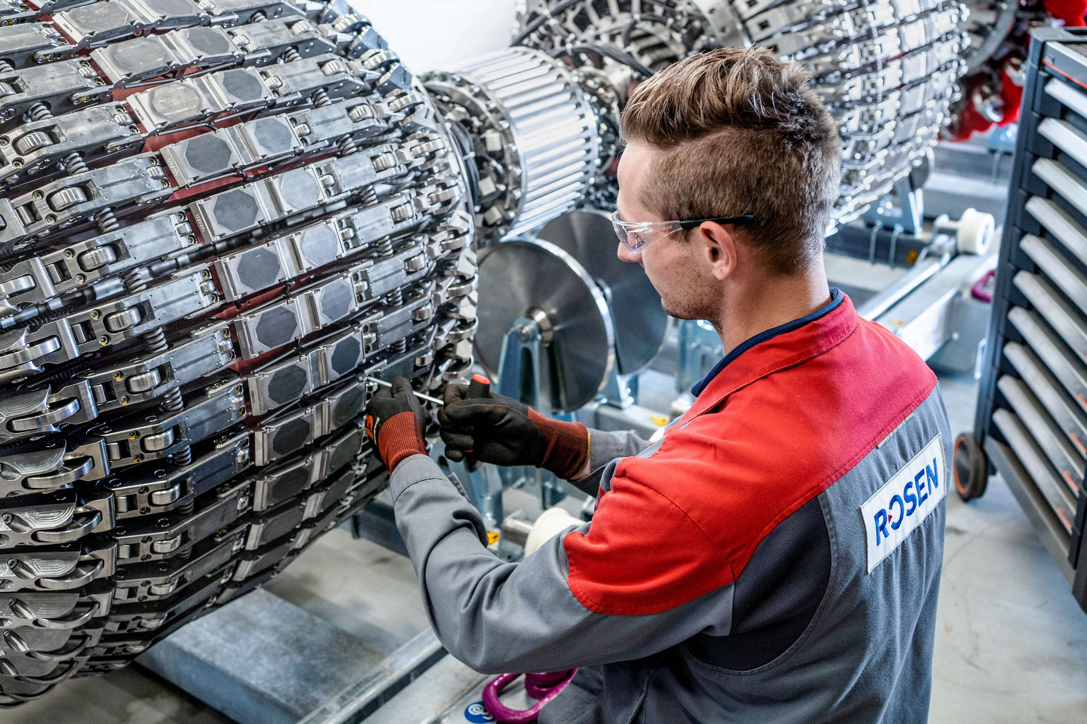 Young man with safety goggles screwing on a ROSEN inspection tool.