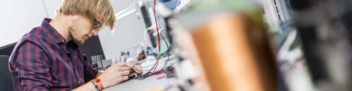 Mann sitzt auf einem Schreibtisch und arbeitet an Sensoren