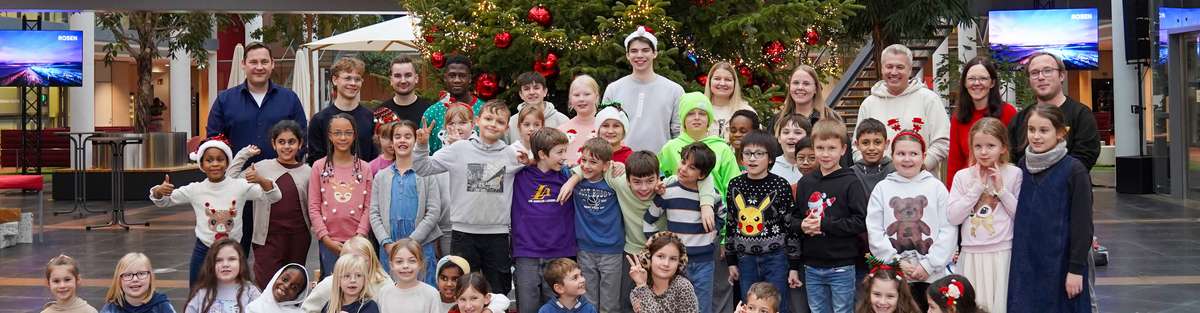 Many people (children and adults) in front of a Christmas tree at the donation handover.