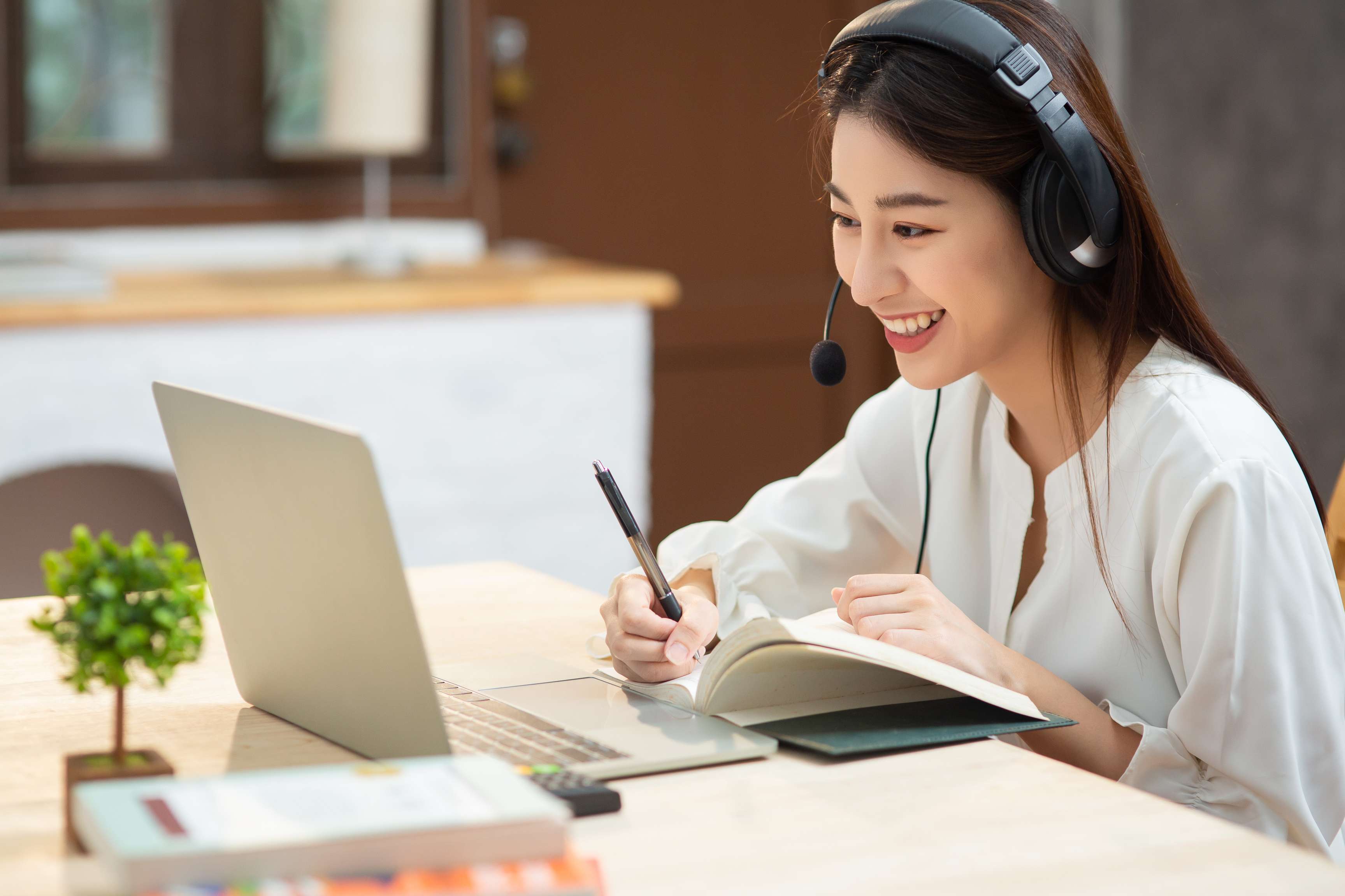 Woman sitting in front of laptop with headset and laughing.