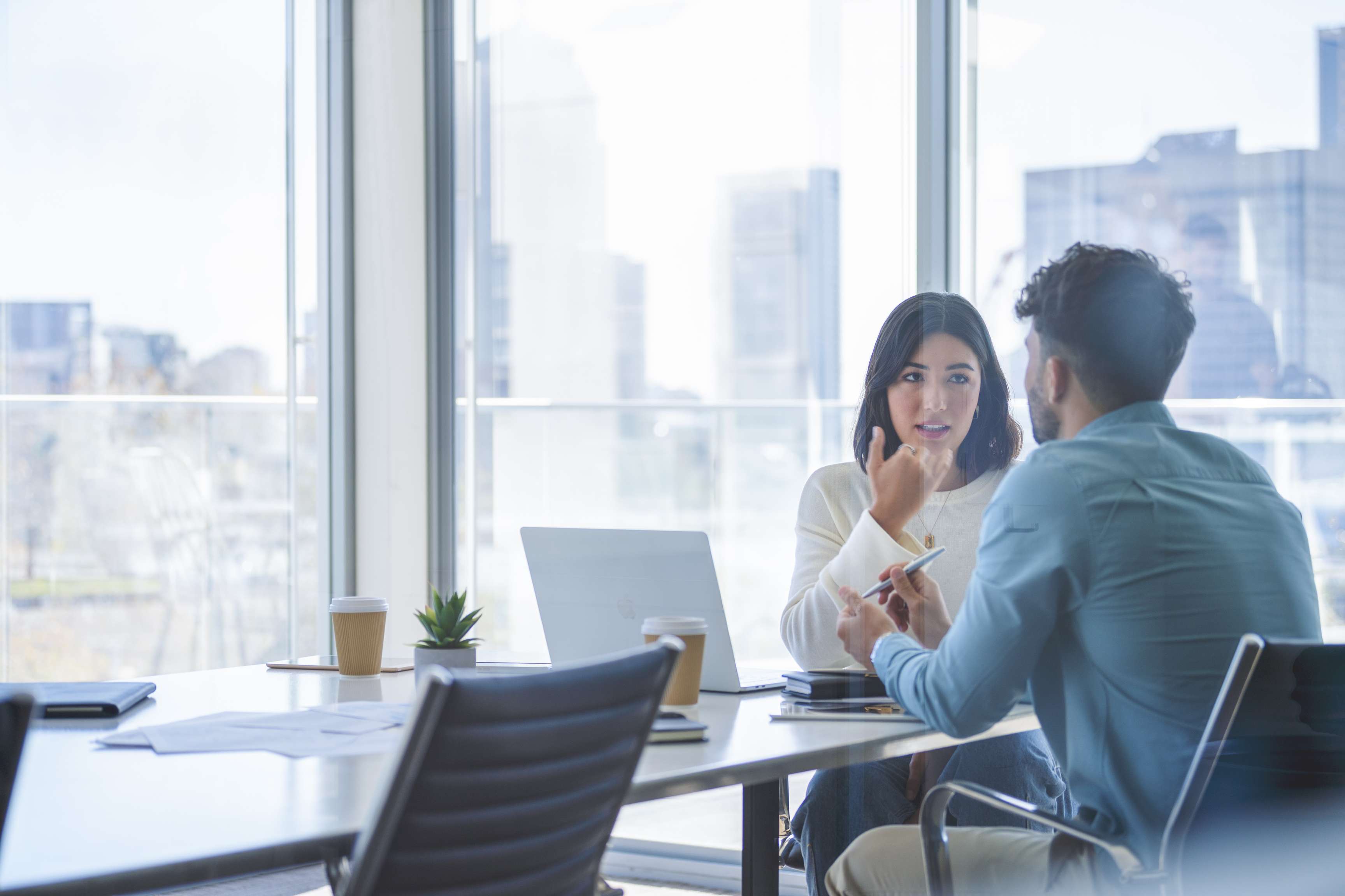 Two people sitting in a meeting room talking to each other.