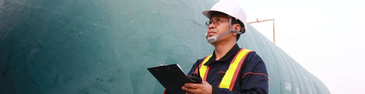 Field technicians standing at a pipeline with a checklist.