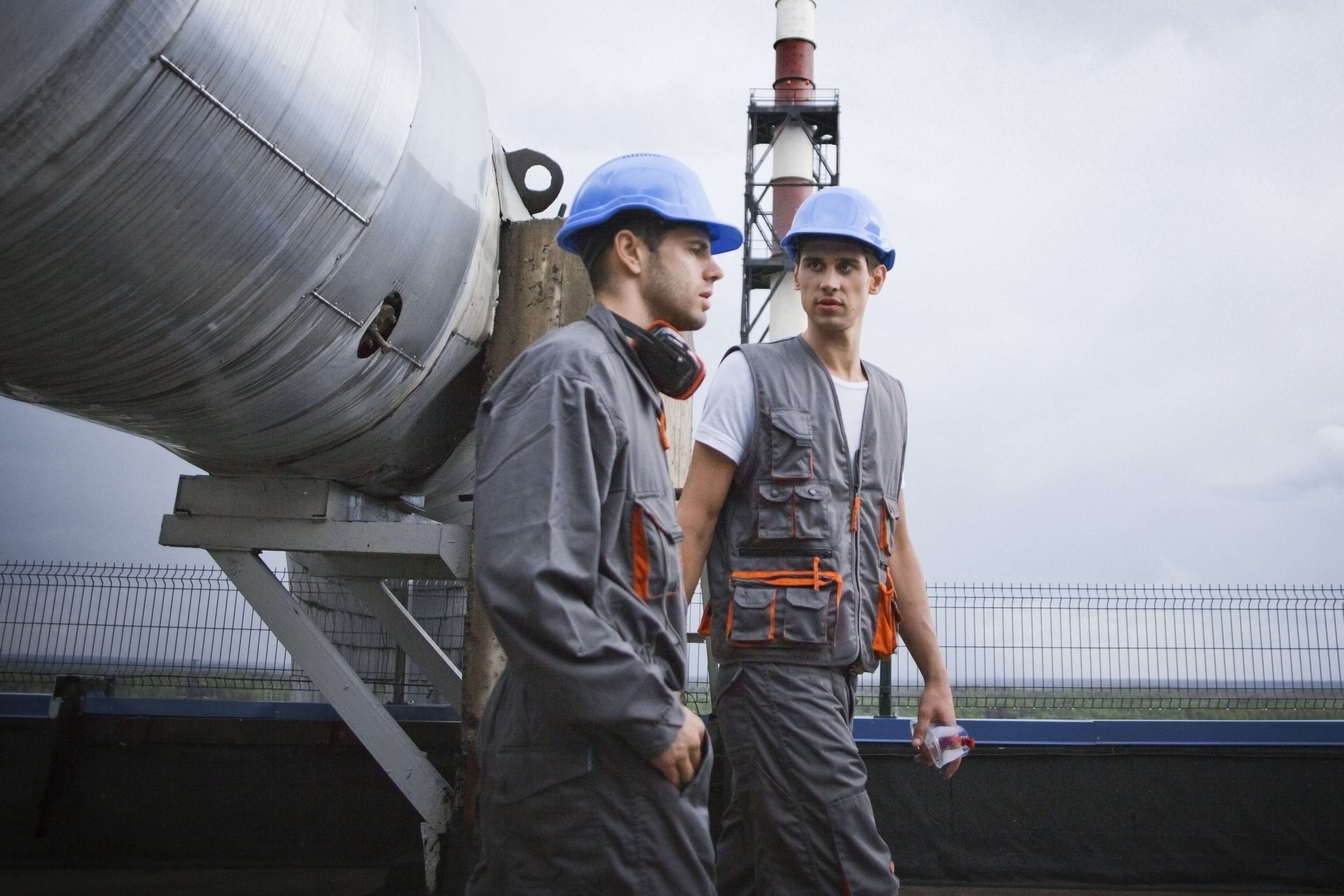 Two employees are walking, behind them is a pipeline.