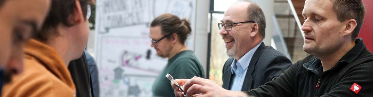 A man is explaining a small tool to a group of people.