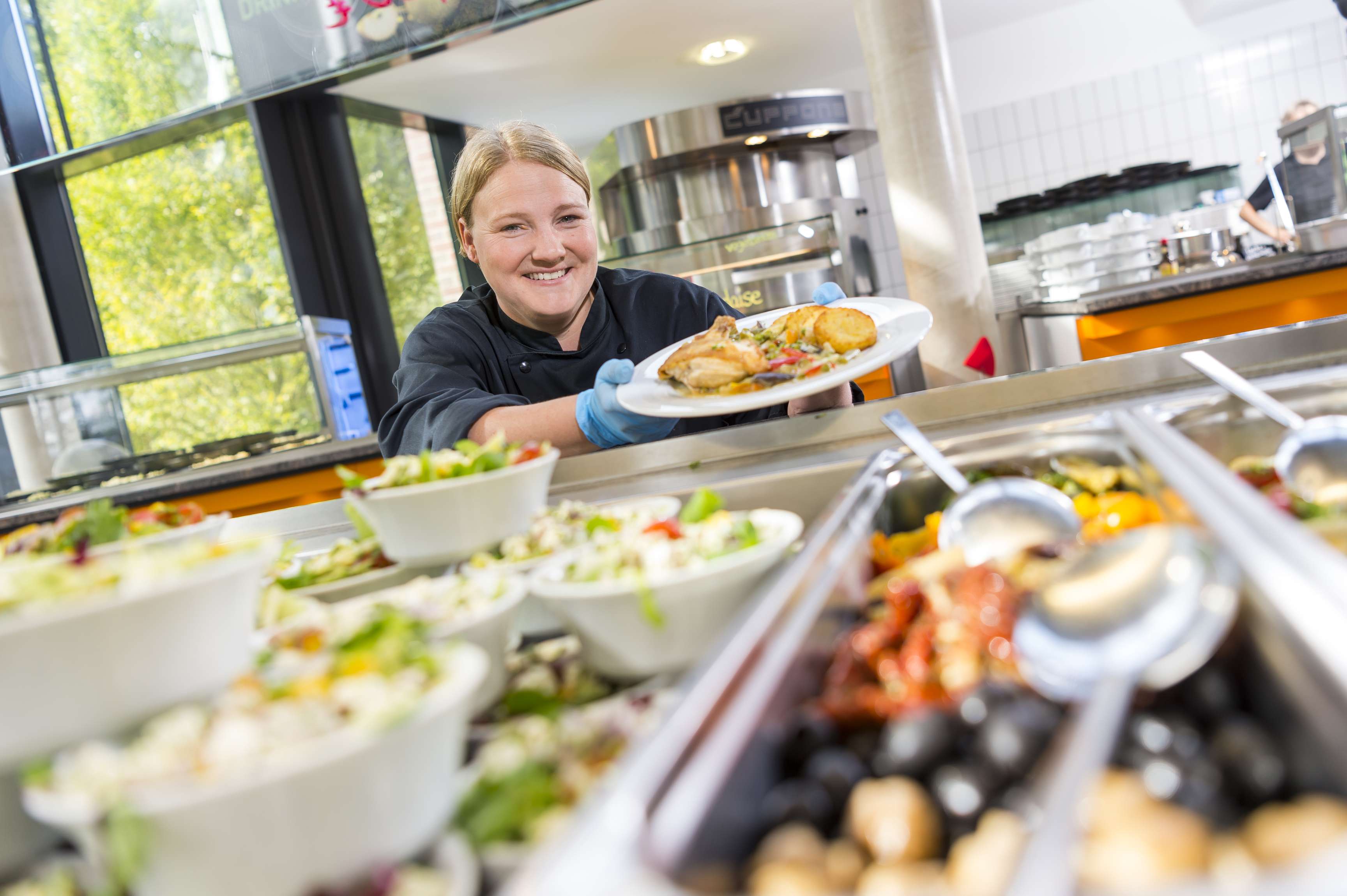 Woman working in the canteen and present plate full of food.