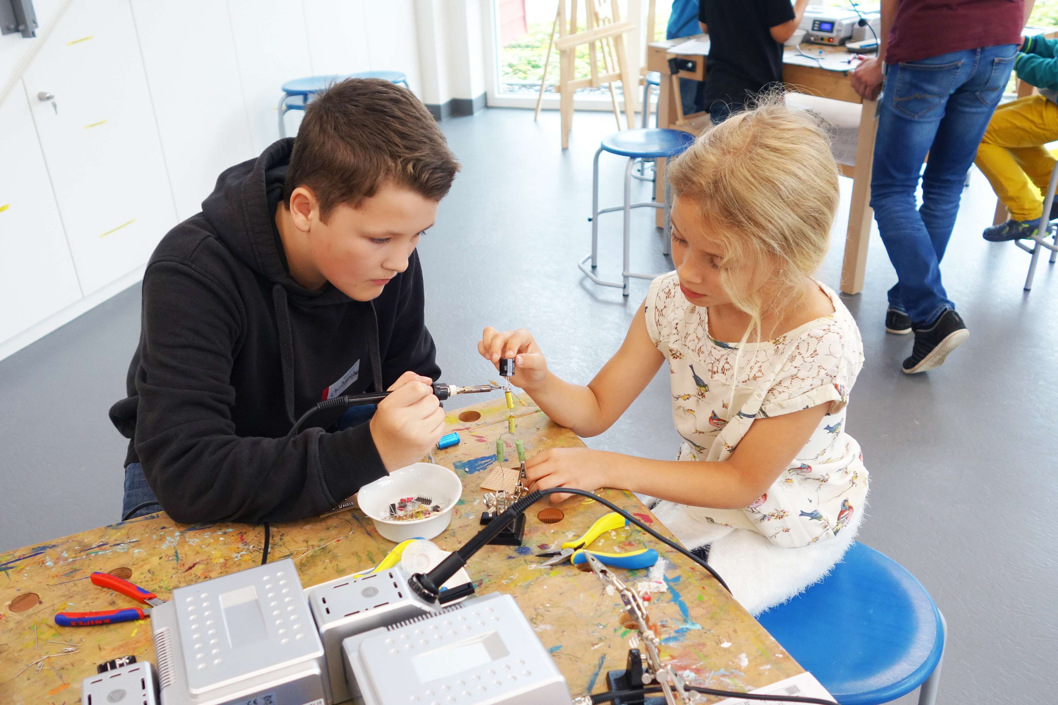 Two children soldering a figure together
