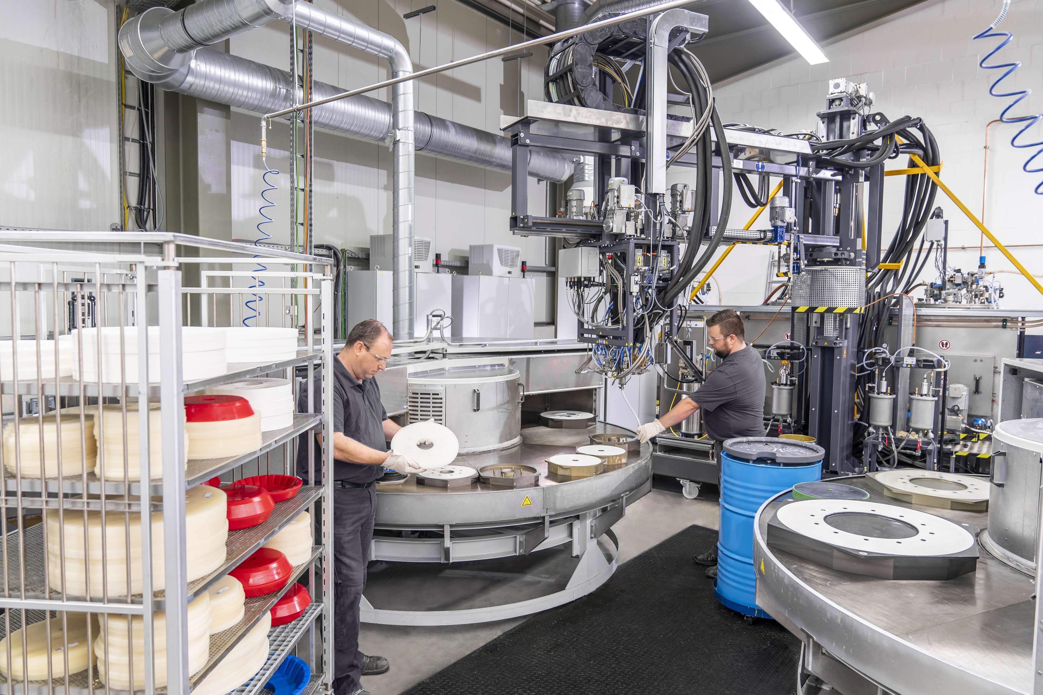 Zwei ROSEN Mitarbeiter stehen an einer Maschine an der Tool-Bauteile, Kunststoffscheiben, gefertigt werden.
