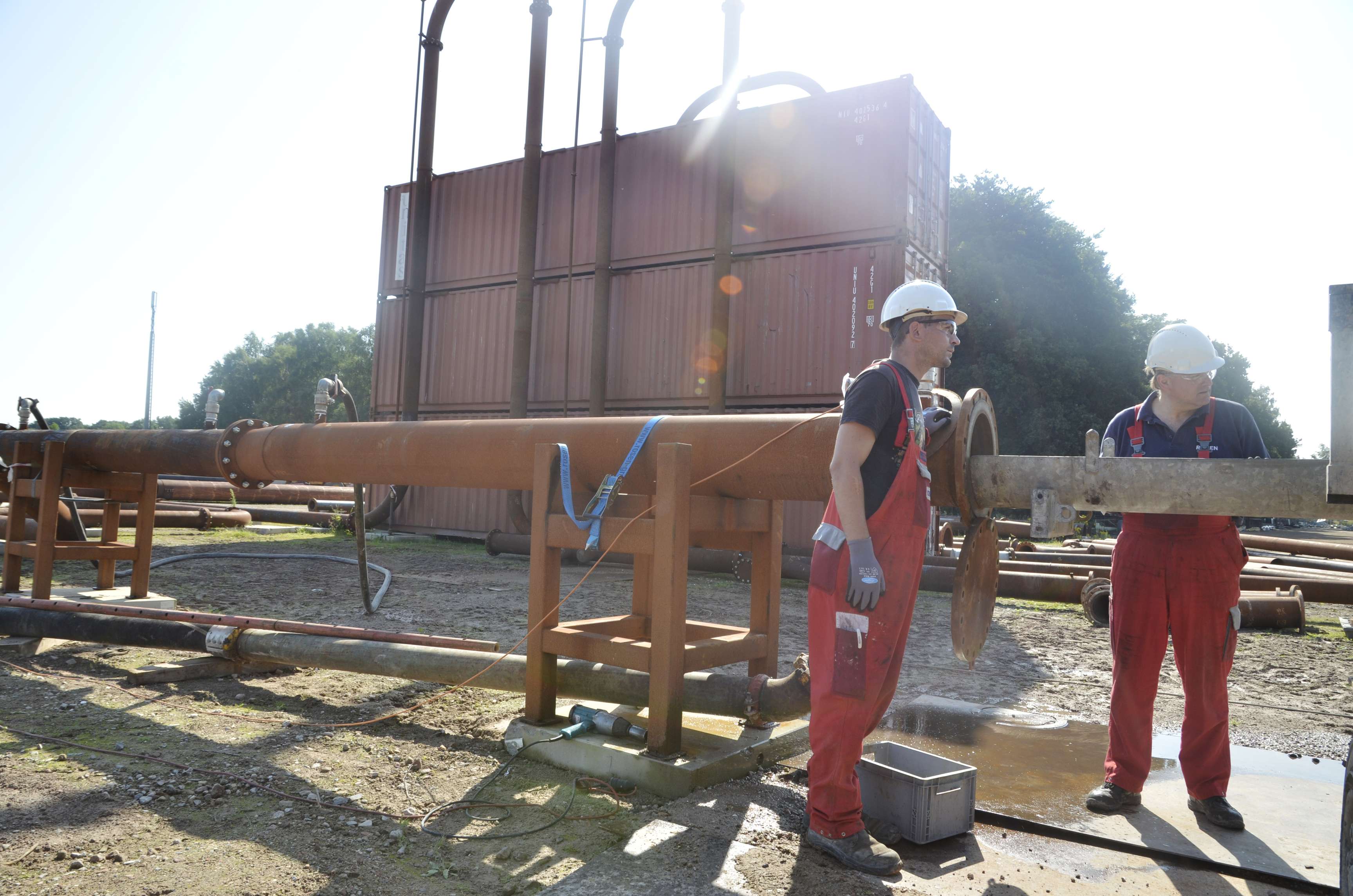 Two employees at a test field inspecting a tool.