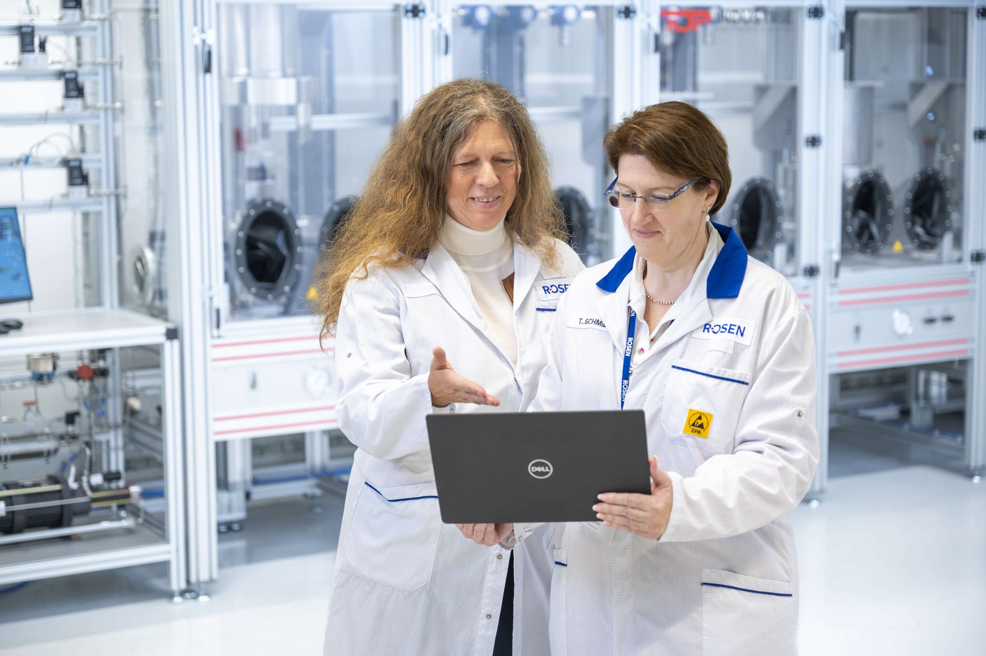 Two employees look at a laptop while standing in the hydrogen lab.