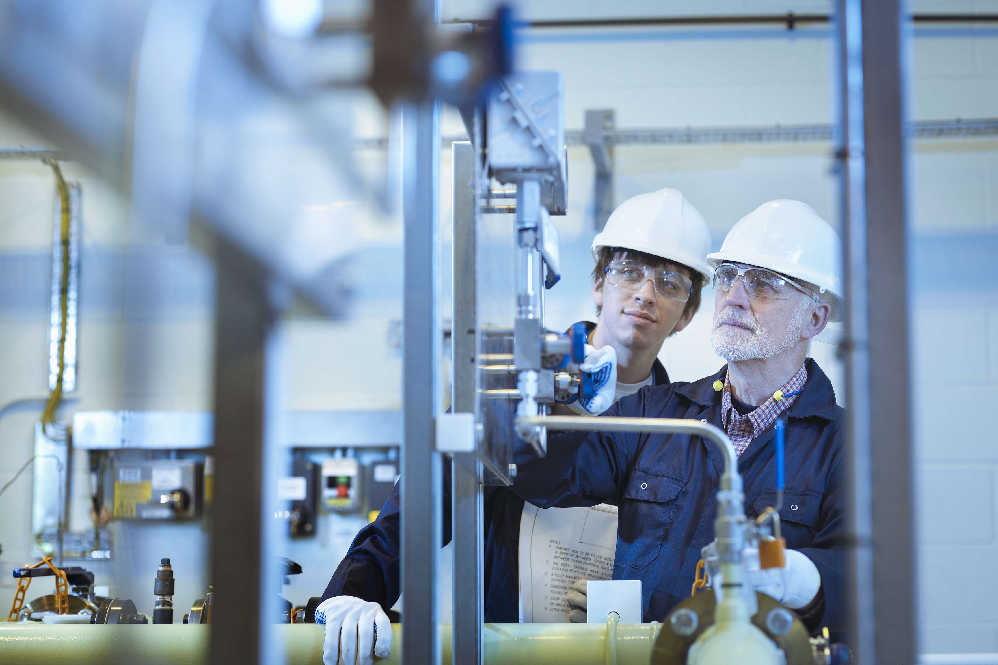 Senior and apprentice engineers working in power station.