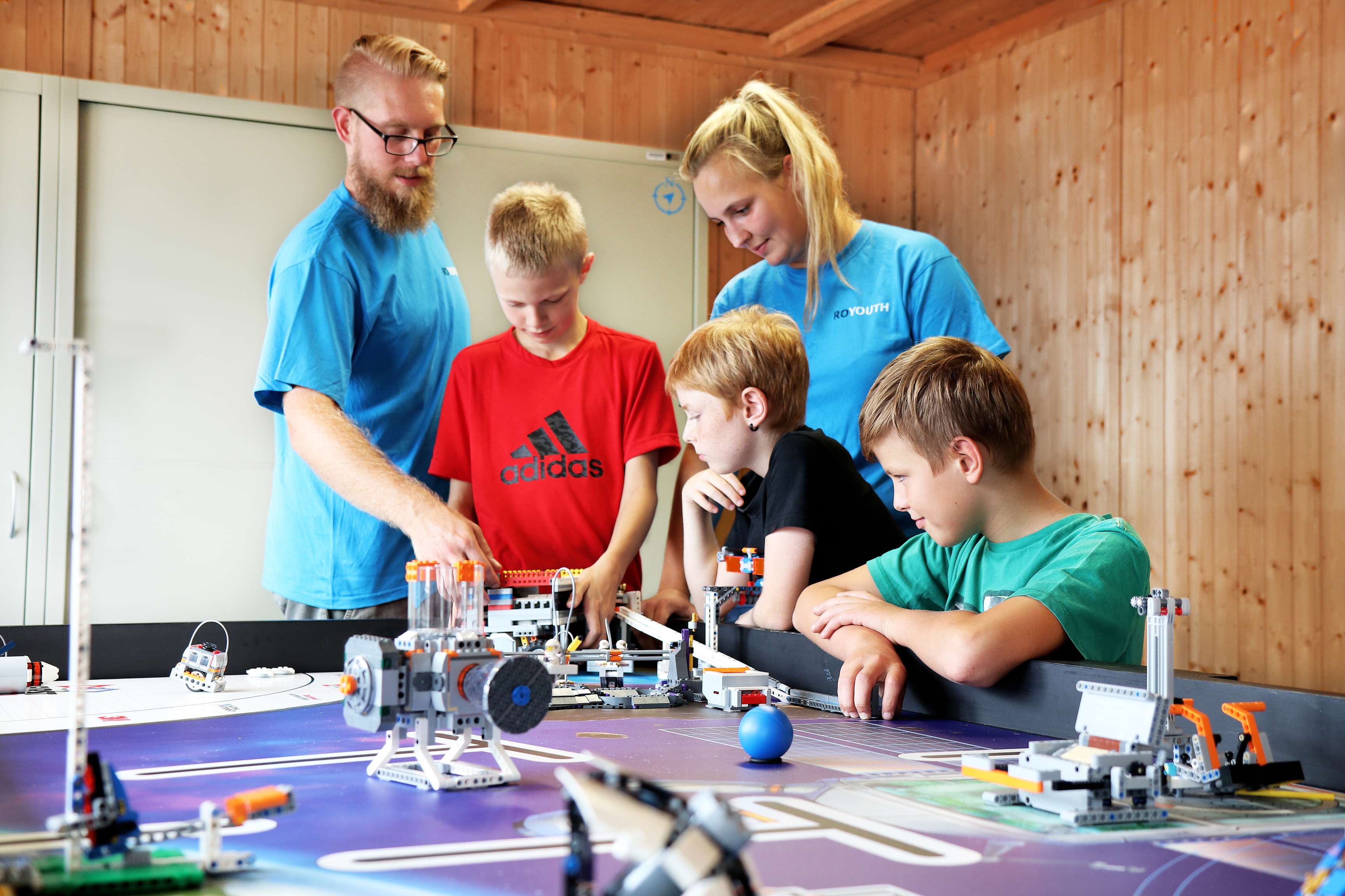Several children and ROYOUTH employees working on projects together.